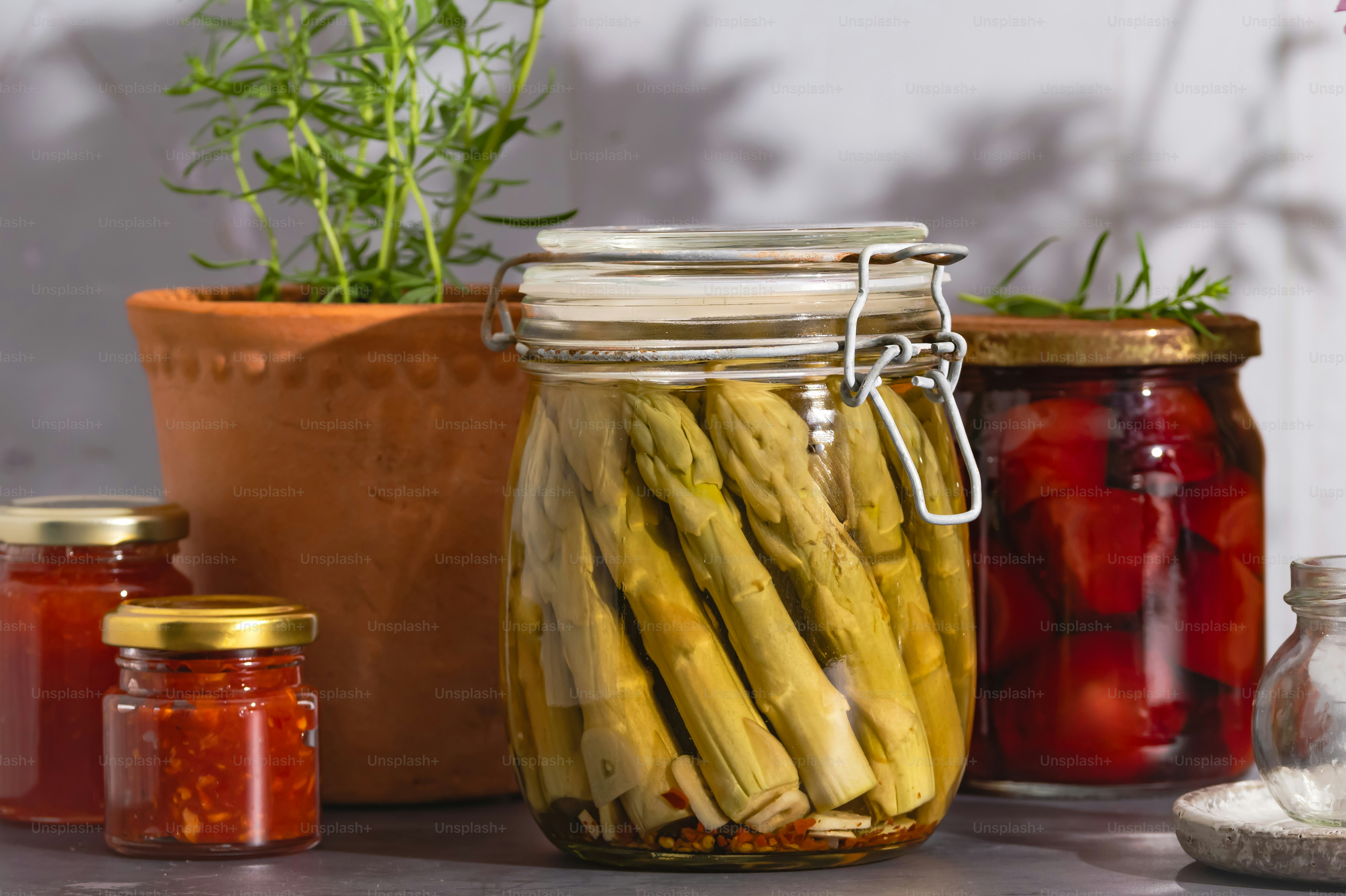 Frascos de verduras y hierbas en escabeche sobre una mesa