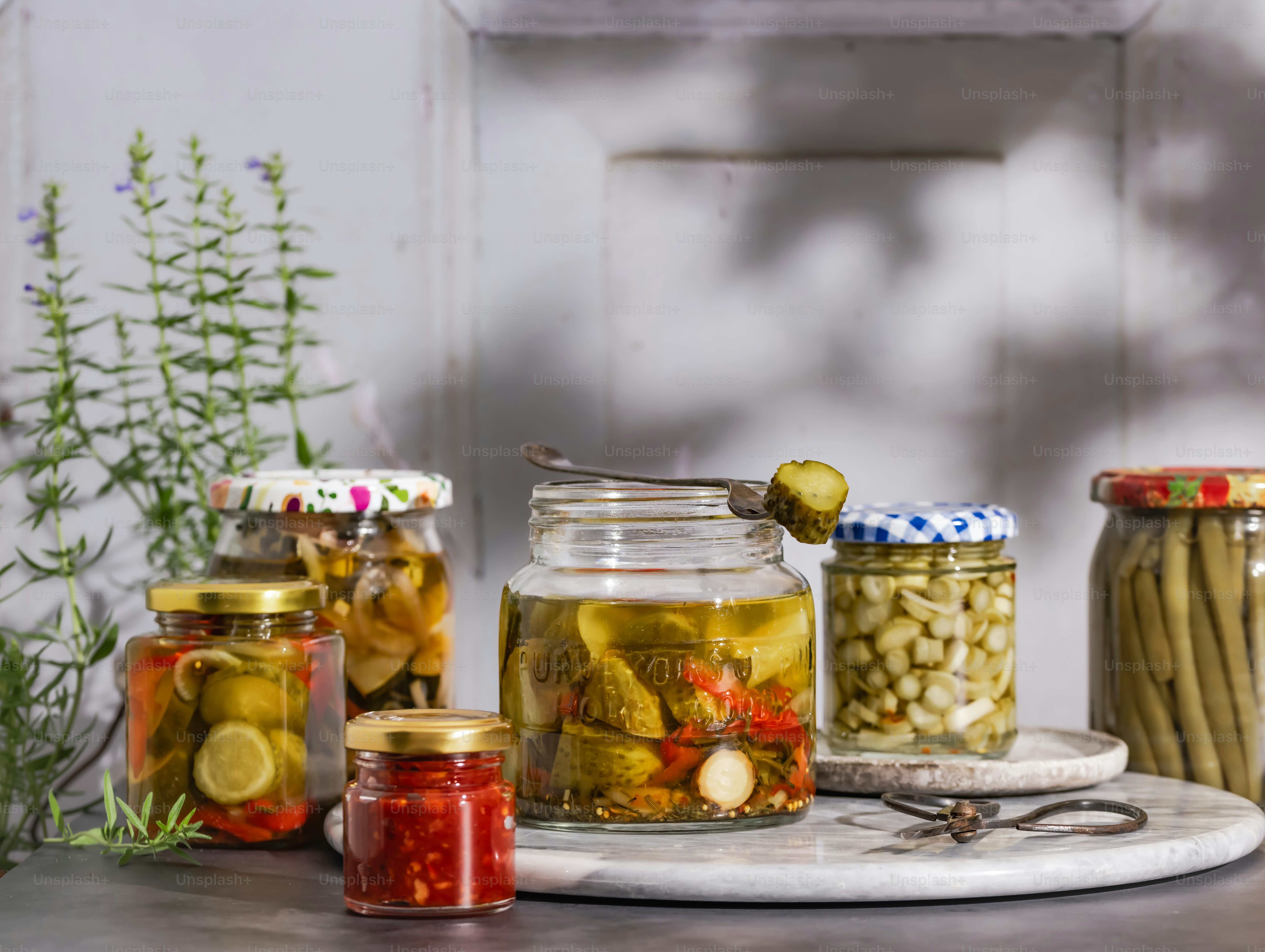 Una mesa cubierta con frascos llenos de encurtidos y pepinillos