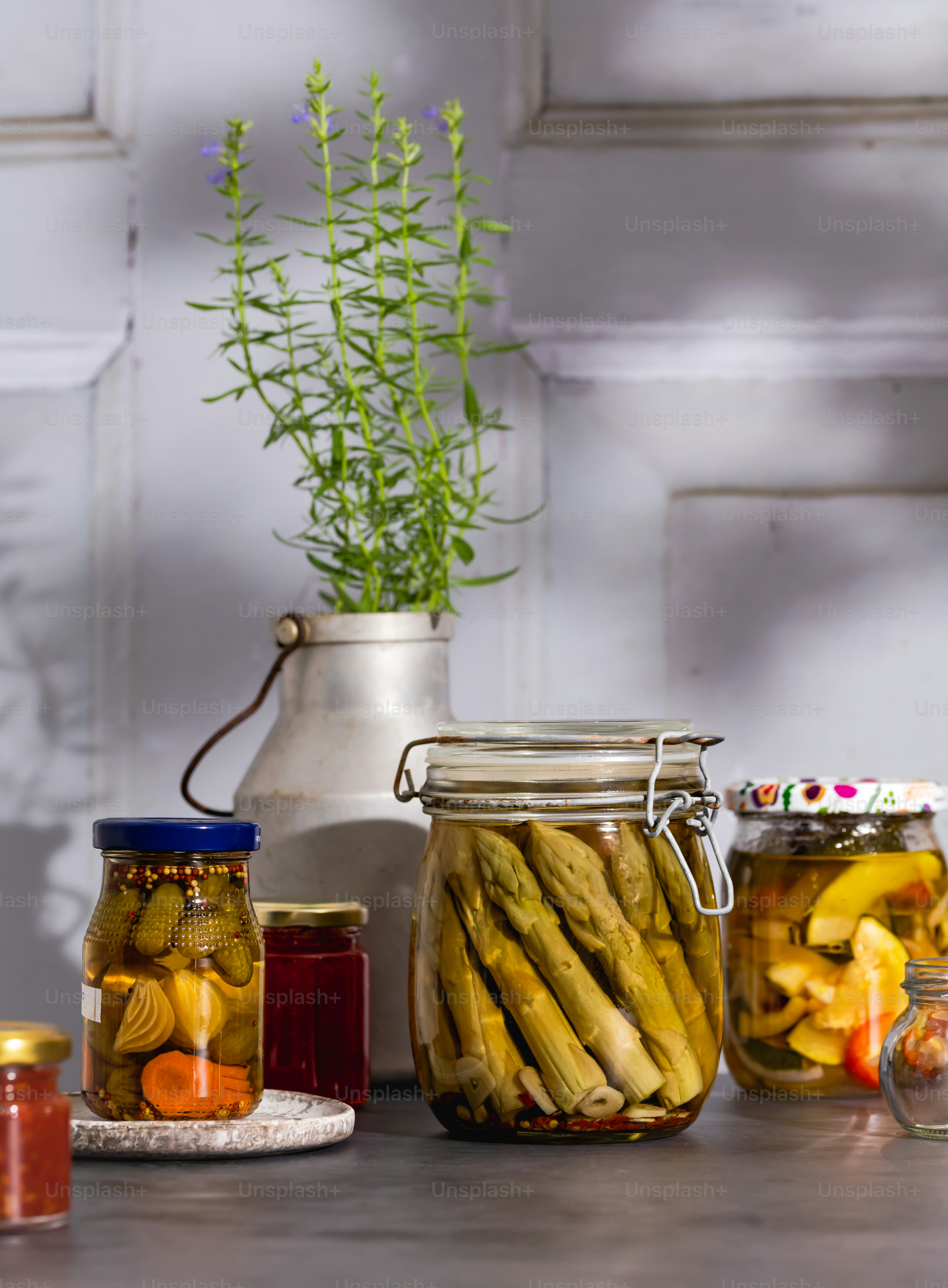 Una mesa cubierta con frascos llenos de pepinillos y frutas