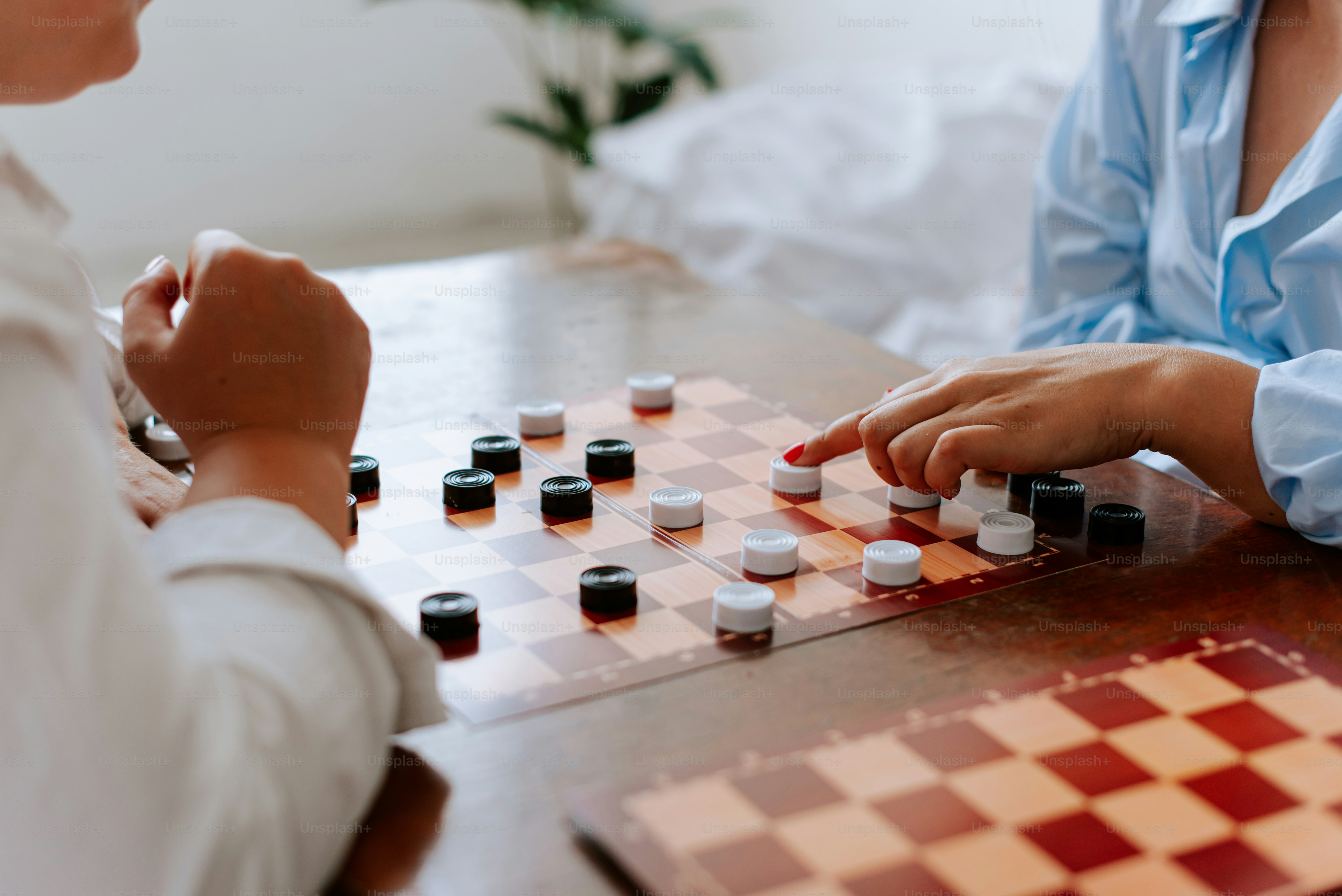 Two women playing a game of checkers on a table