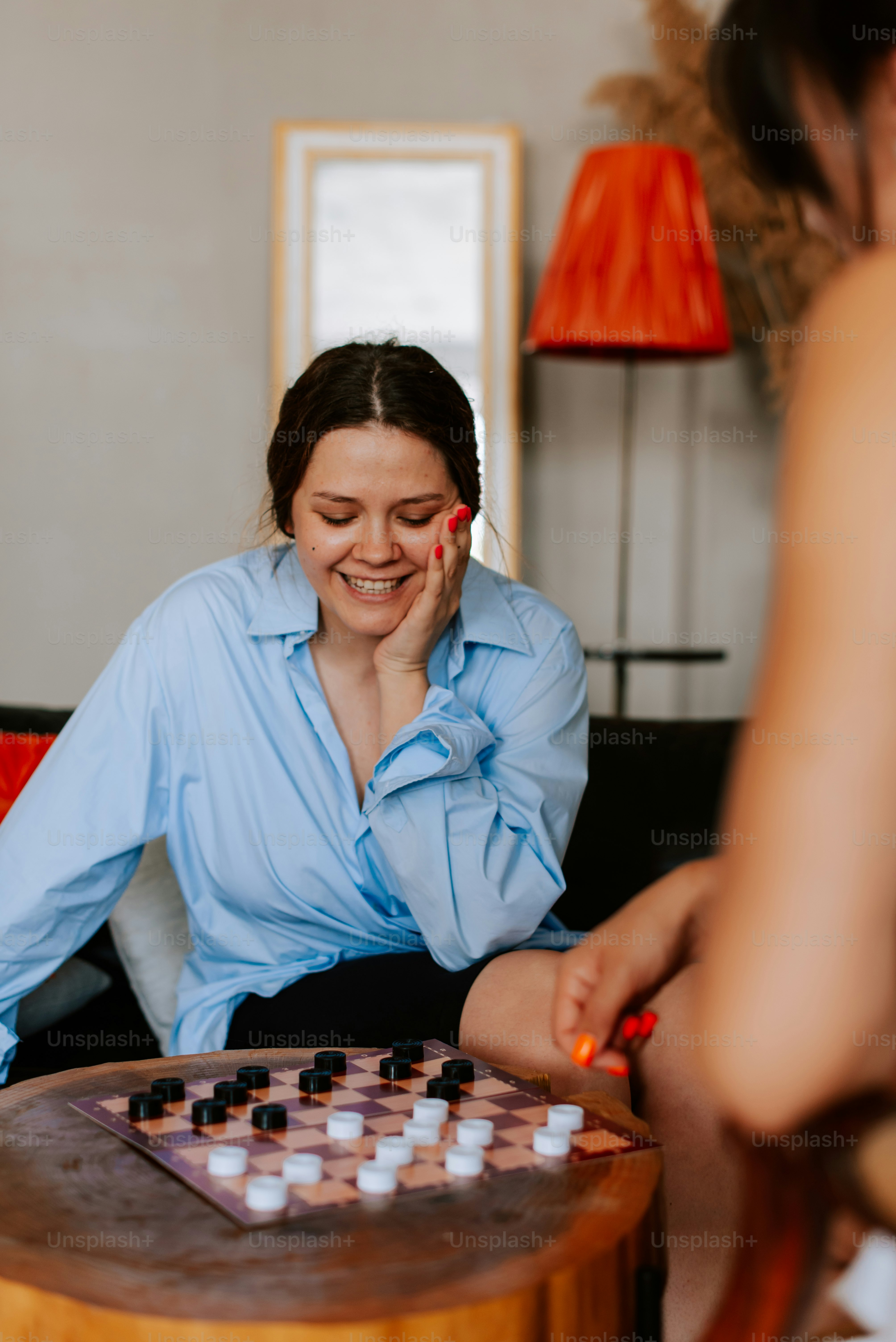 A woman sitting on a couch playing a game of checkers