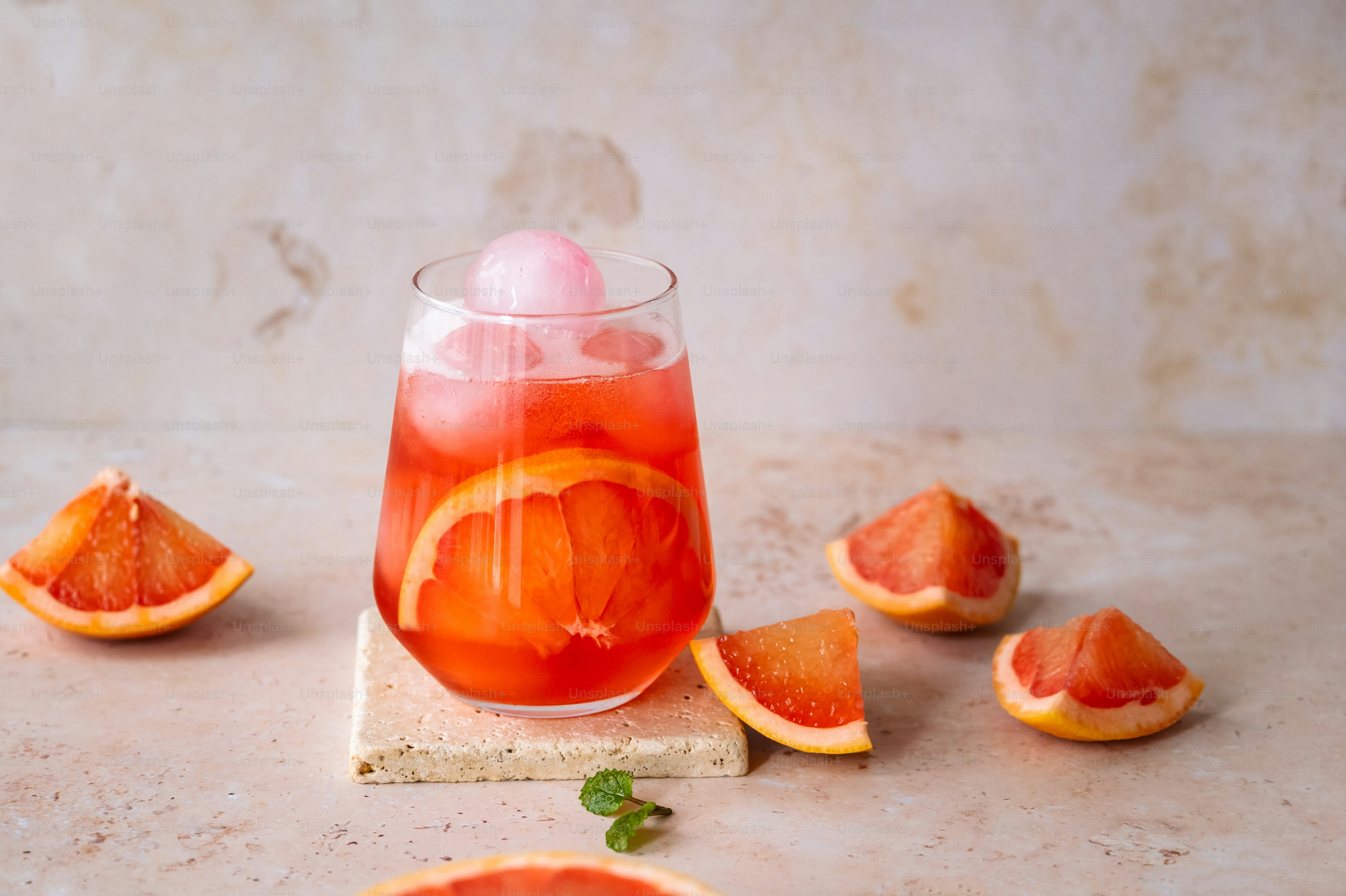 Un vaso lleno de una bebida rodeado de naranjas en rodajas