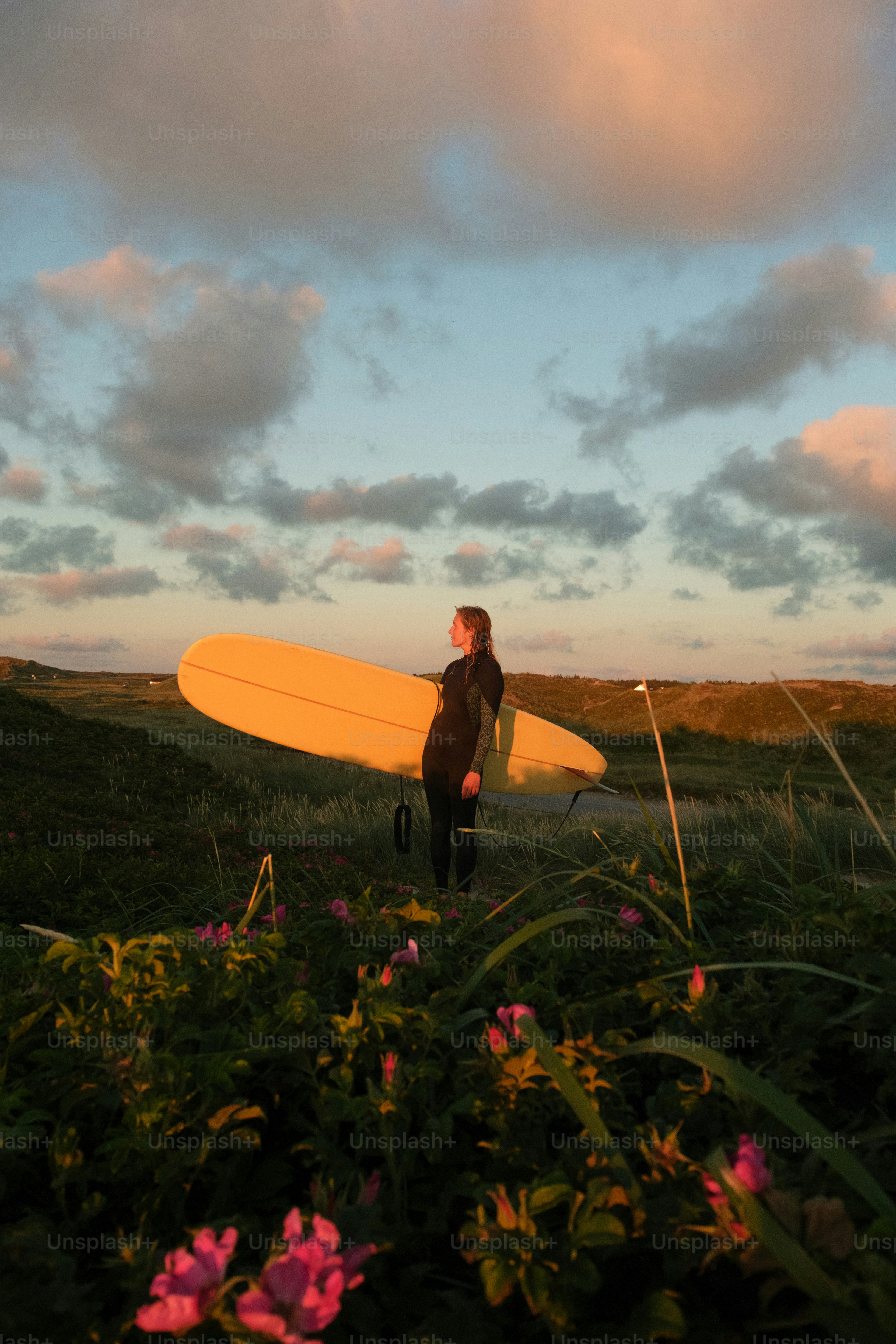 A man holding a surfboard standing in a field