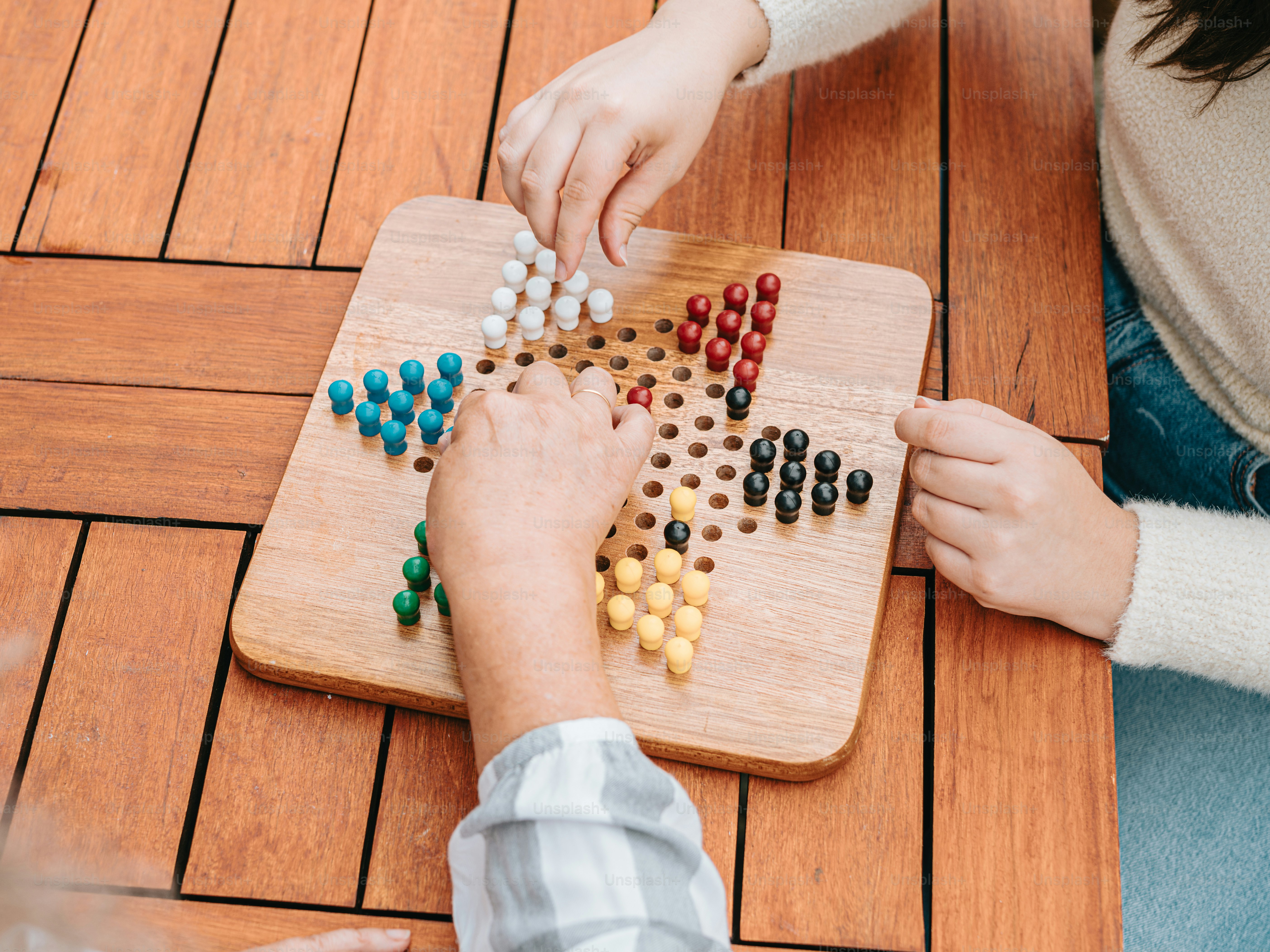 Zwei Personen spielen ein Brettspiel auf einem Holztisch