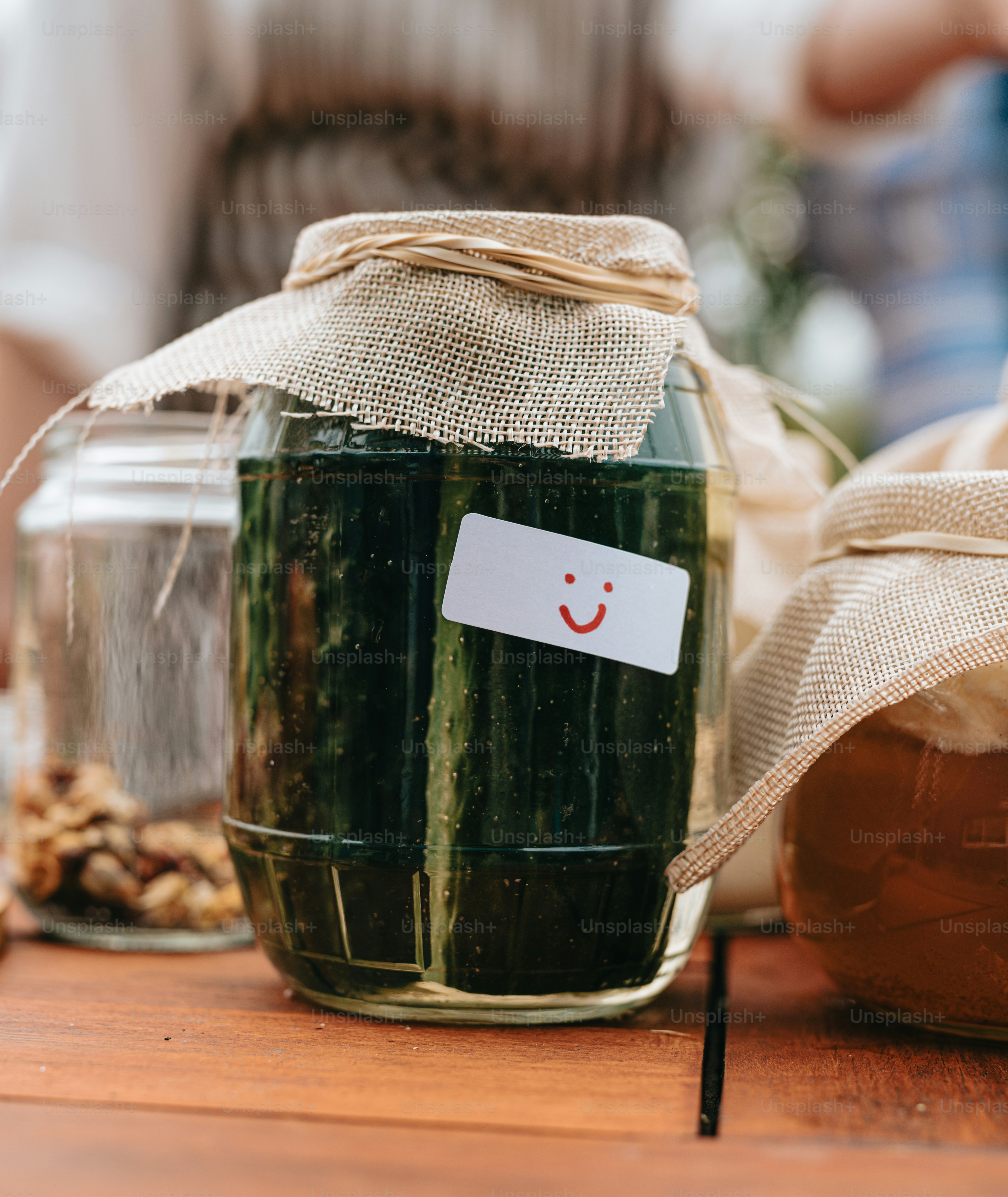 Ein mit Gurken gefülltes Glas steht auf einem Holztisch