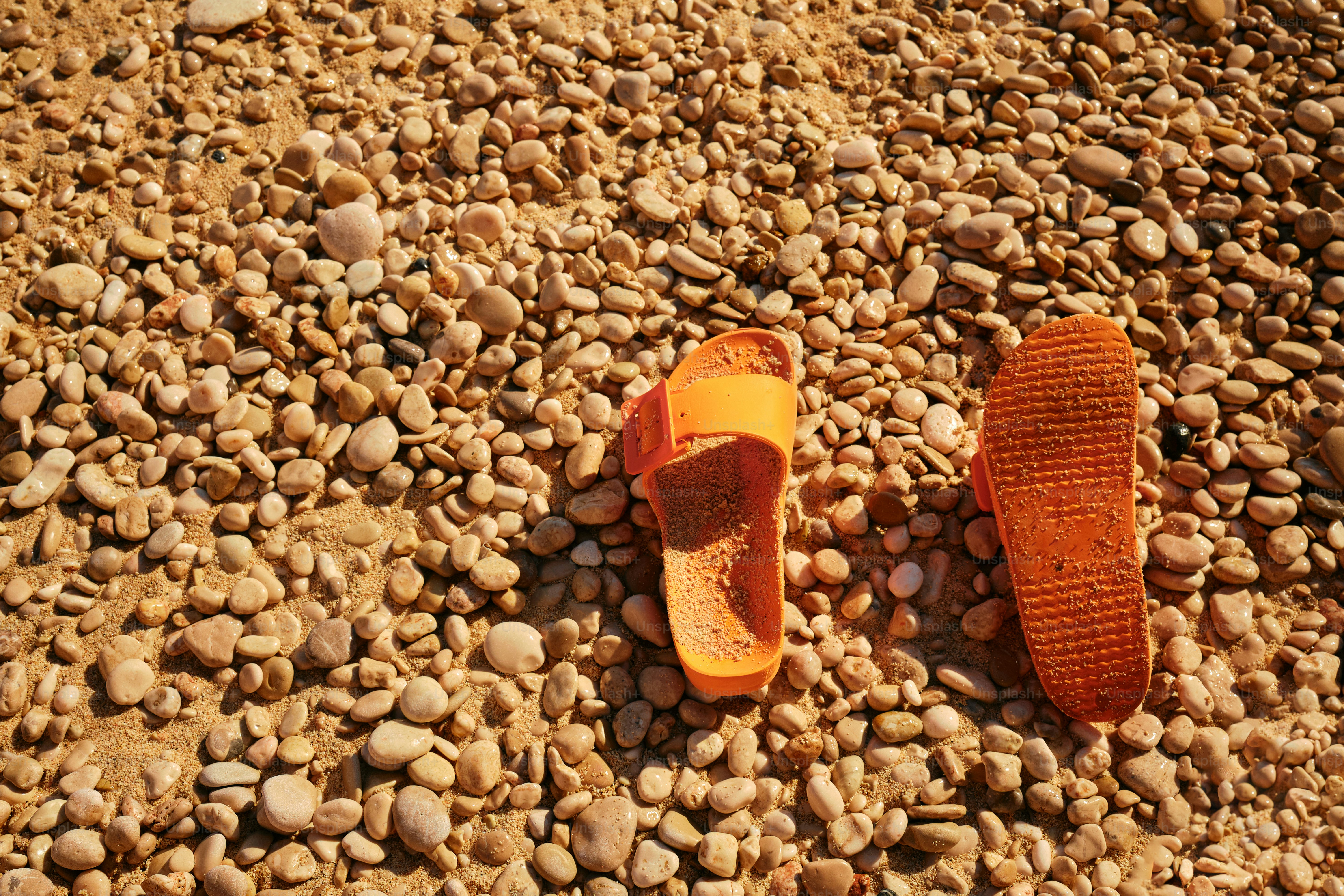 Un par de zapatillas naranjas sentadas en la cima de una playa rocosa