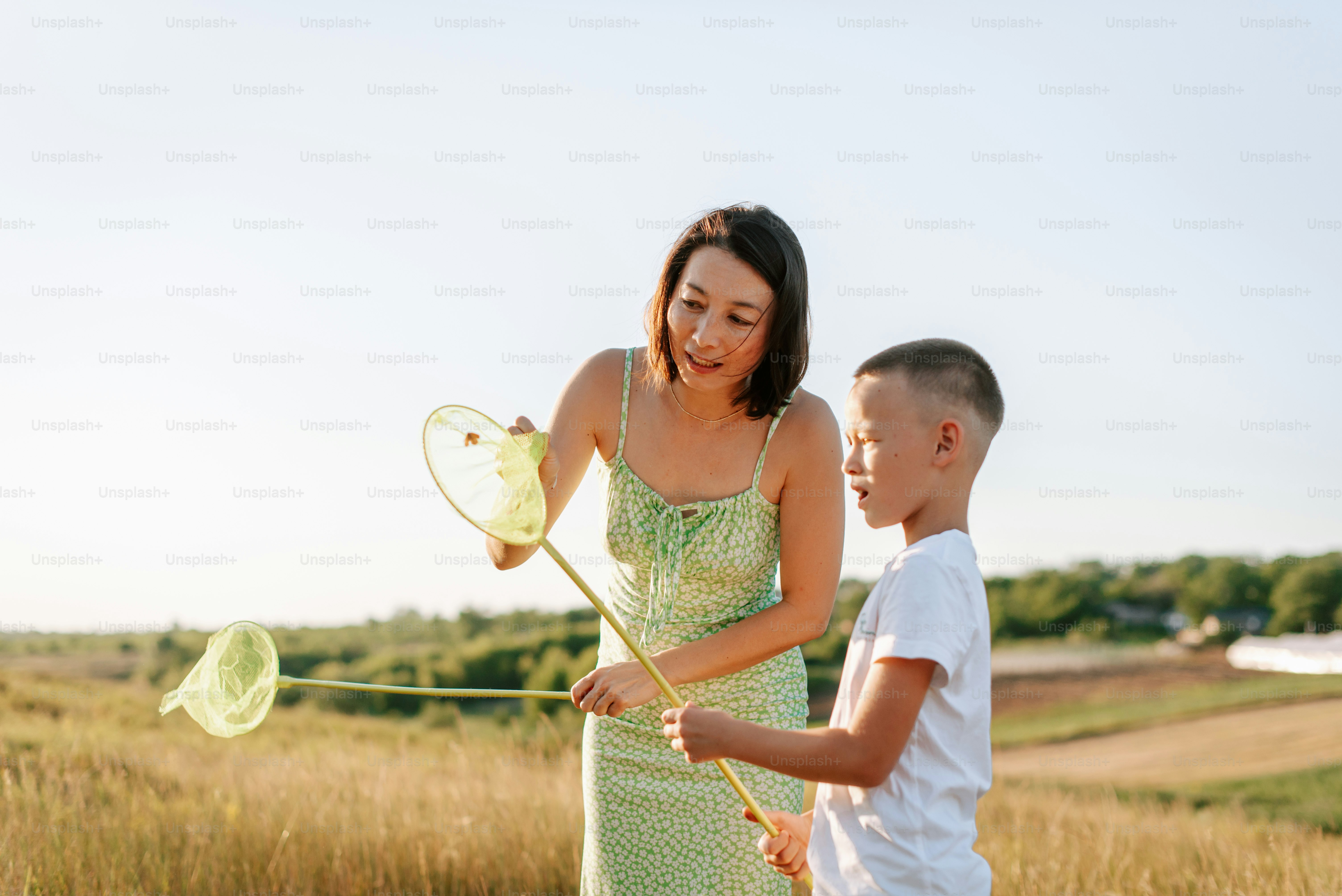 A woman and a boy are playing with kites