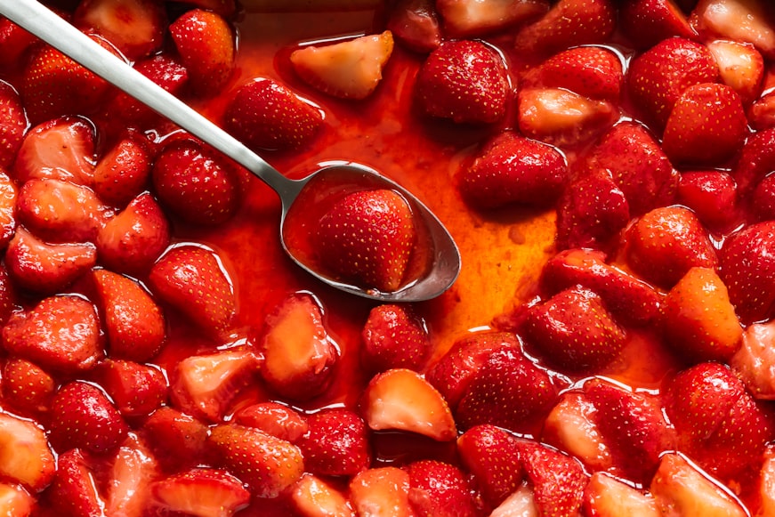 A spoon scooping strawberry sauce
