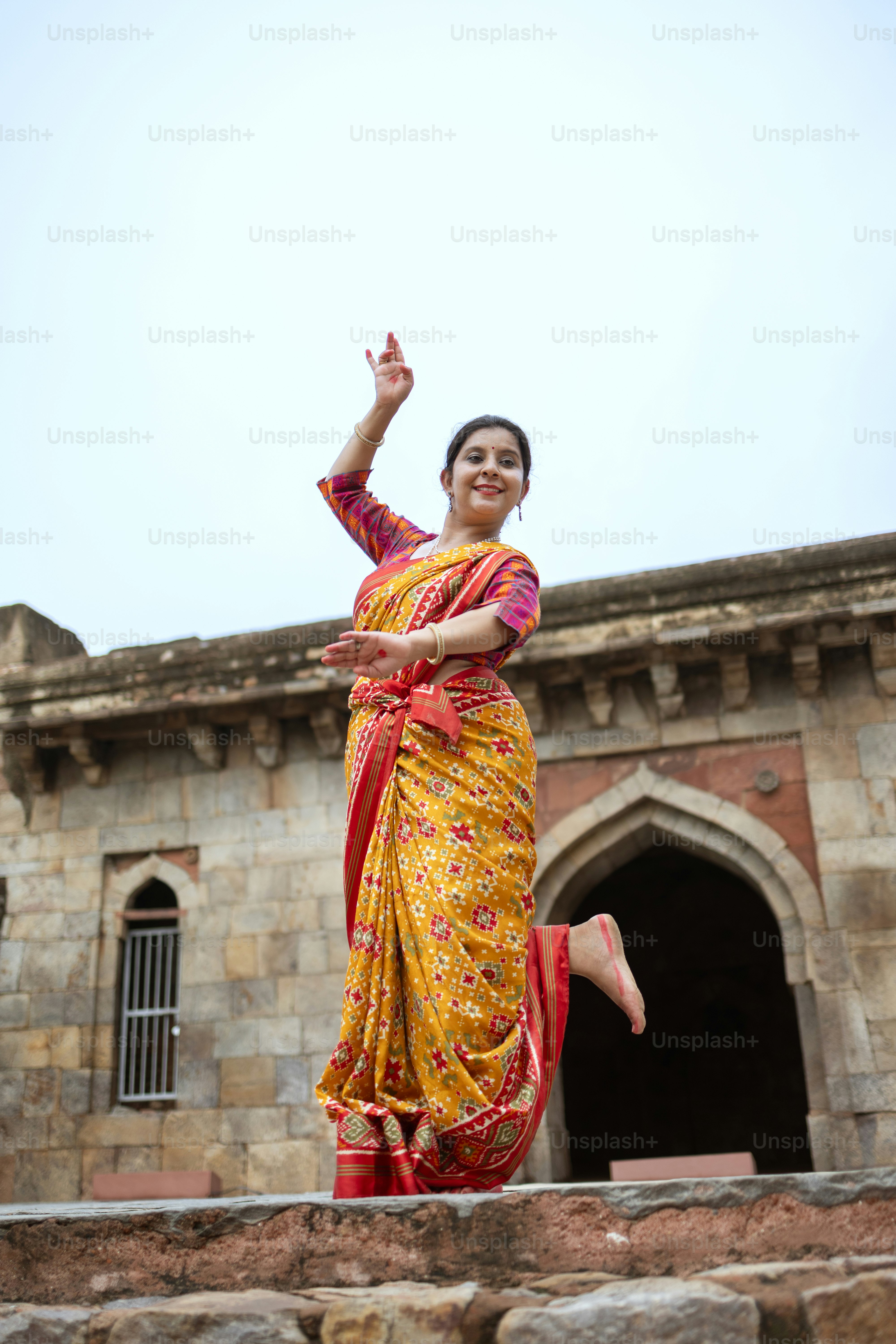 A woman in a yellow and red sari dancing