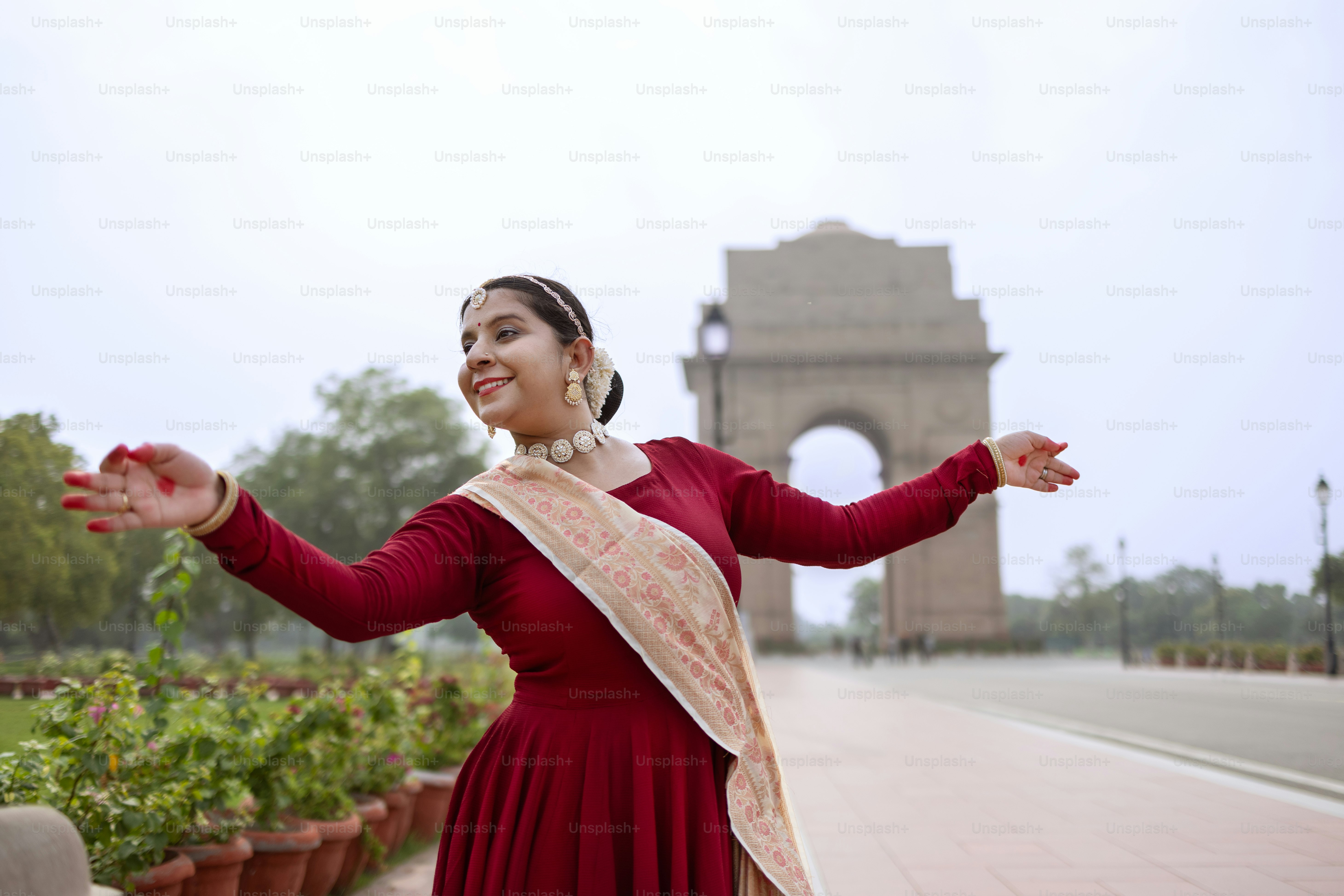 A woman in a red dress standing in front of a monument photo – India ...