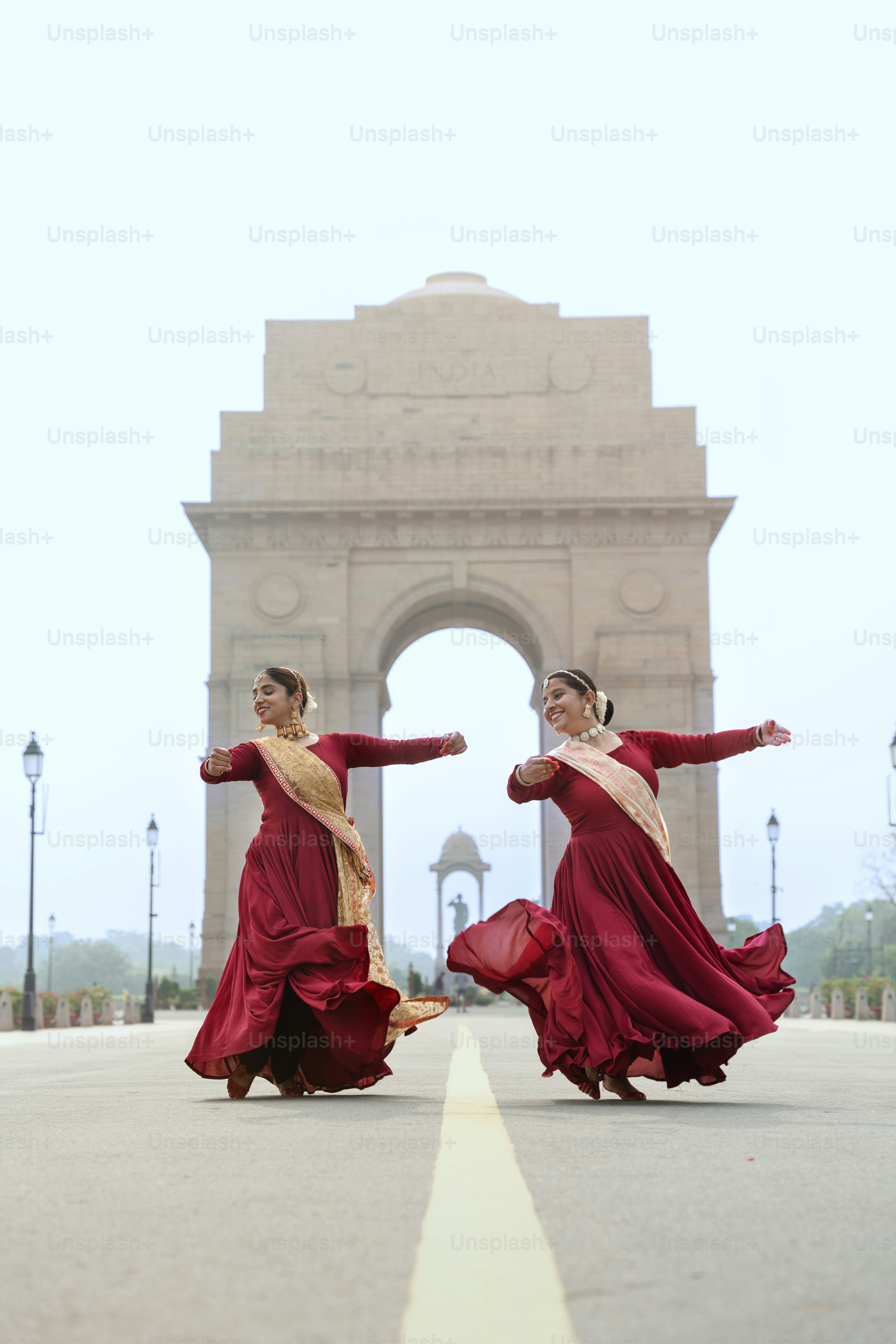 Two women in red dresses are dancing in front of a monument