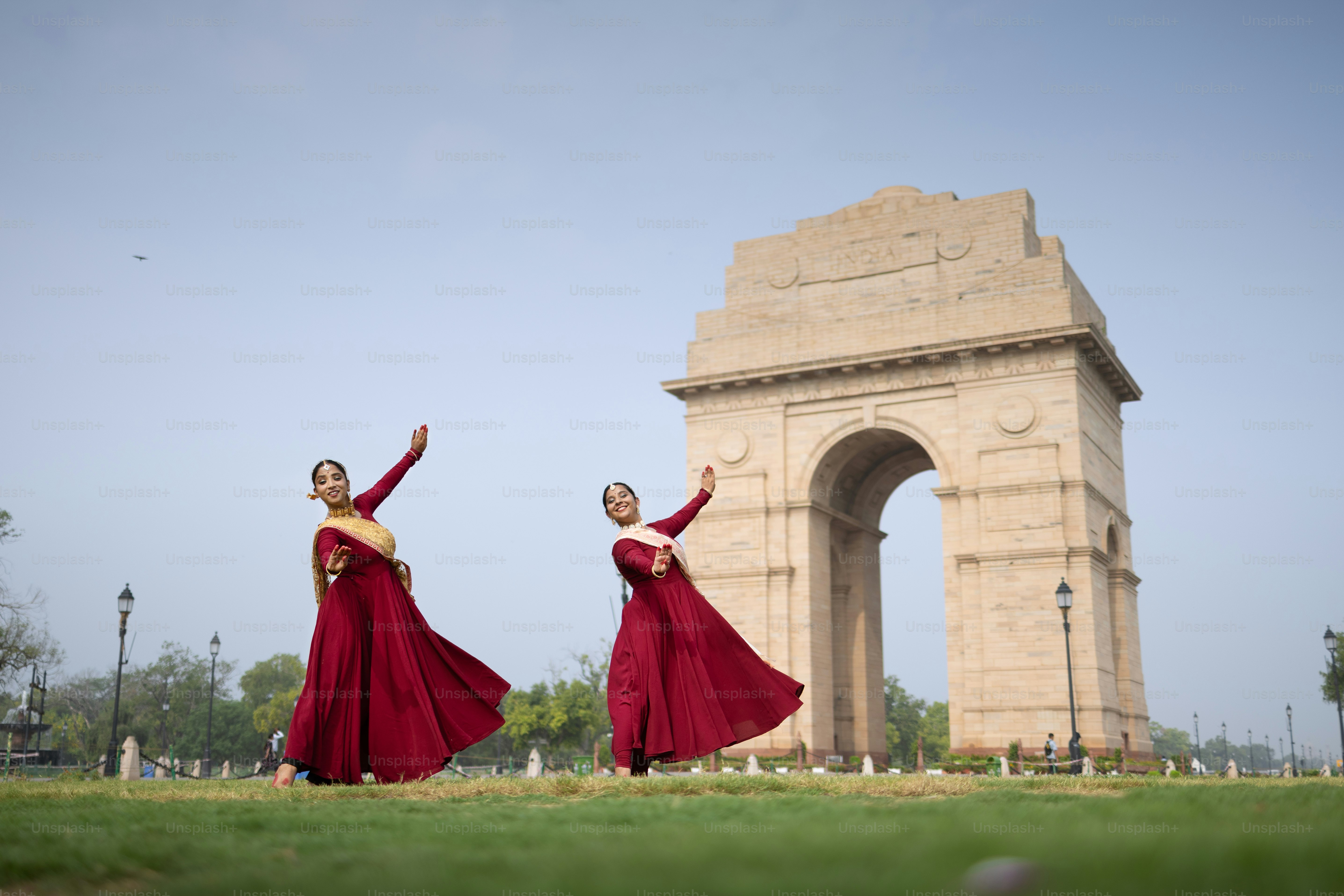 Two women in red dresses are dancing in front of a monument photo ...