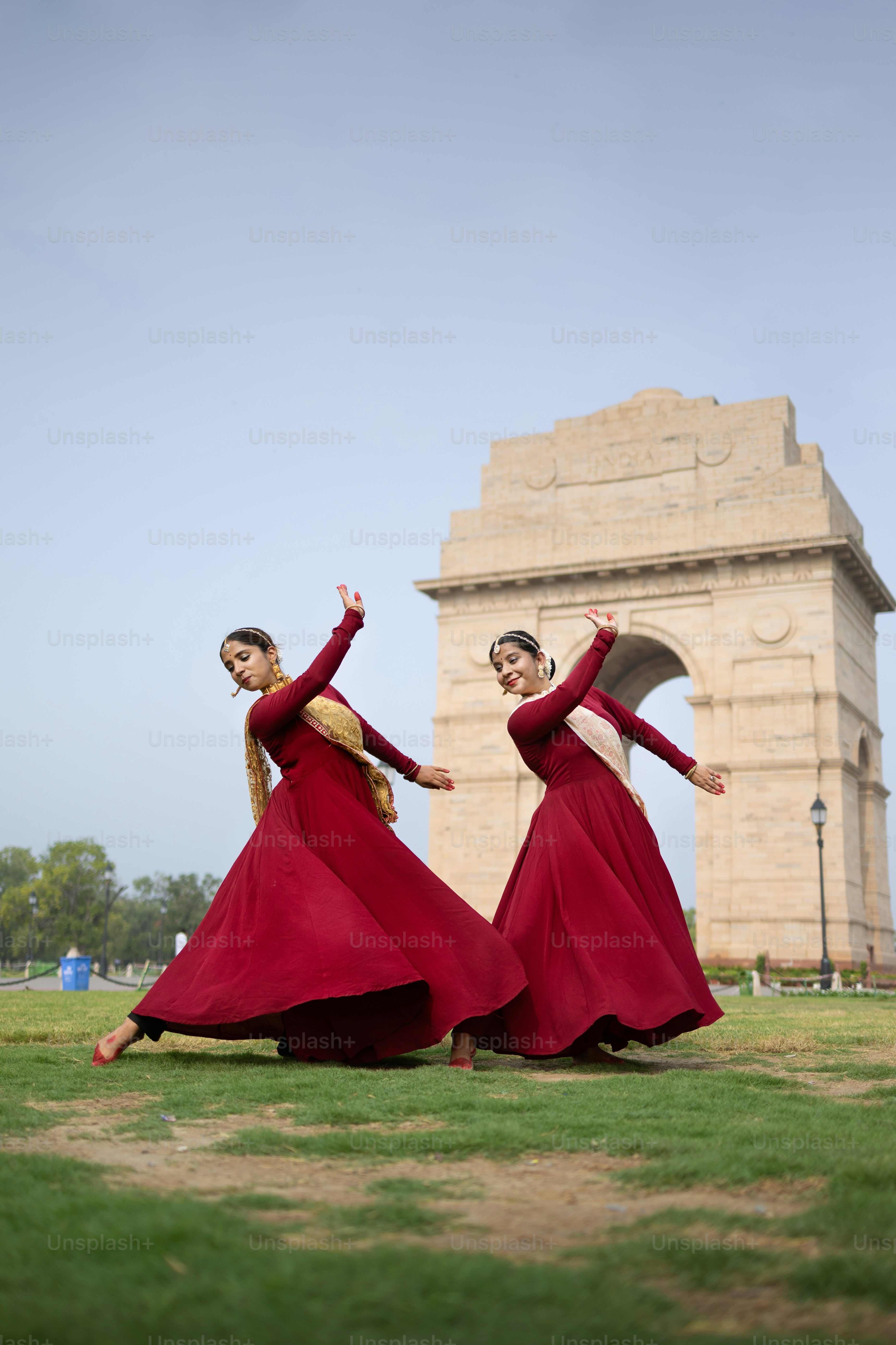 Deux femmes en longues robes rouges dansent devant un monument