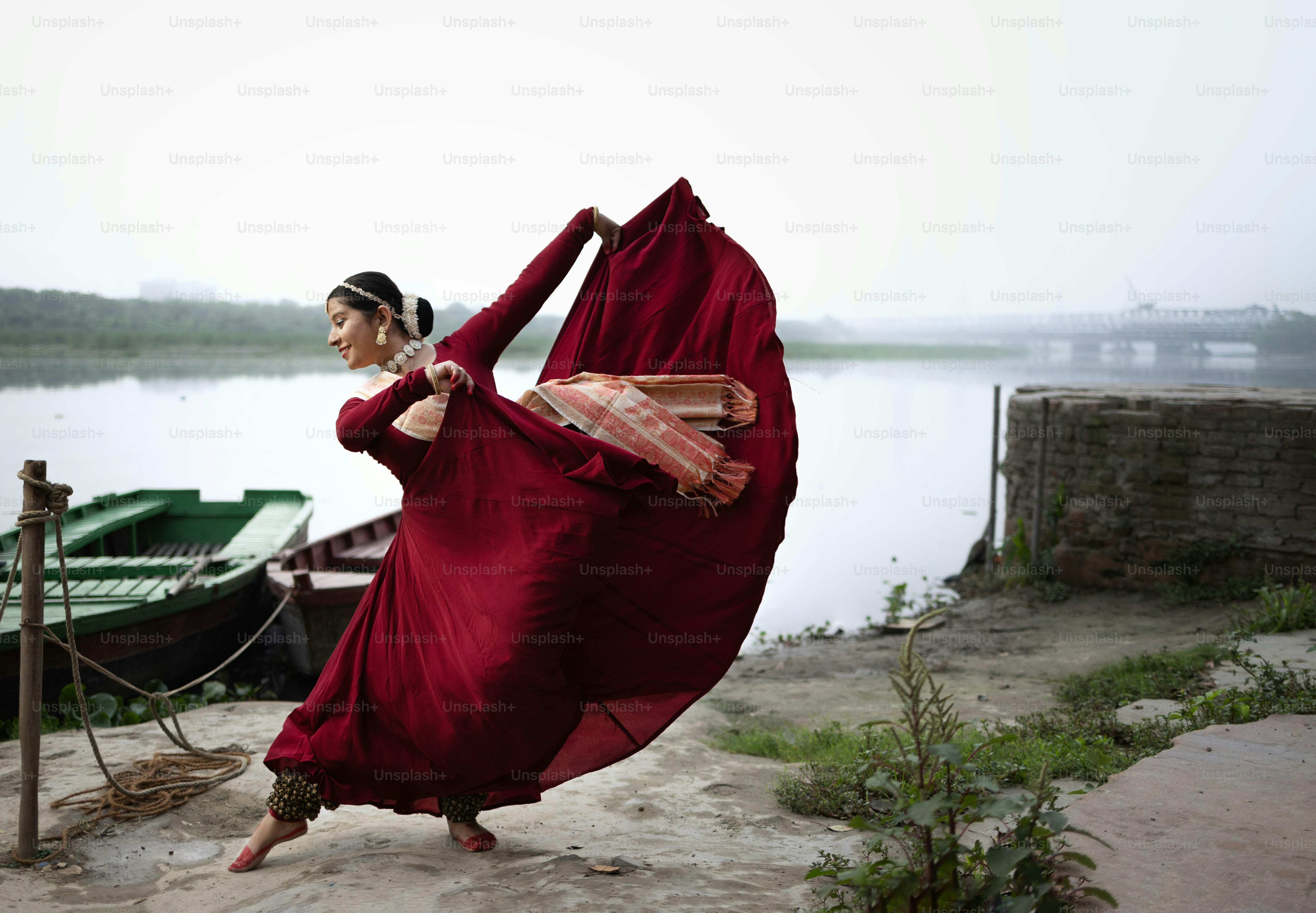 A woman in a red dress is dancing by the water