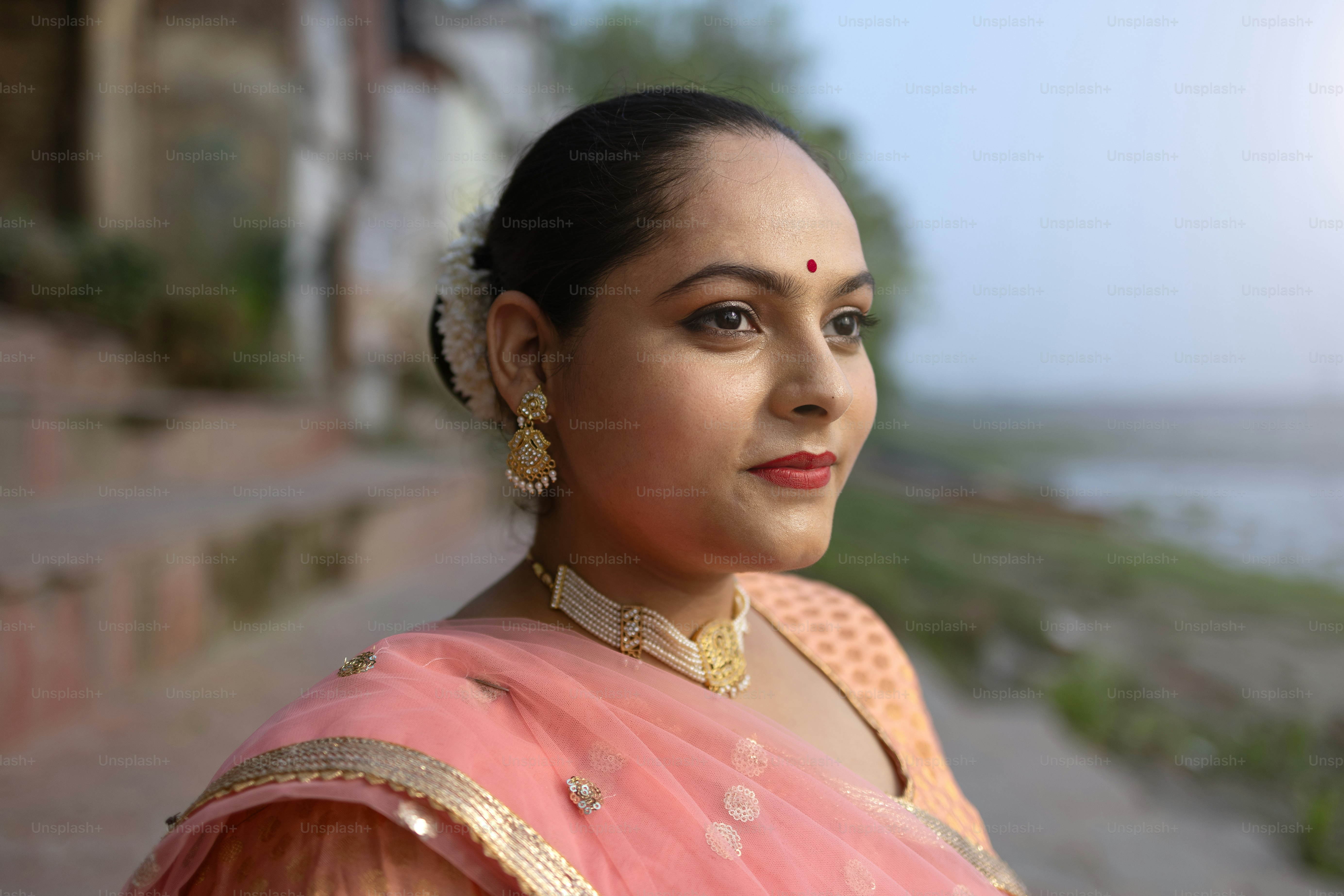 A woman in a pink sari standing on the side of a road