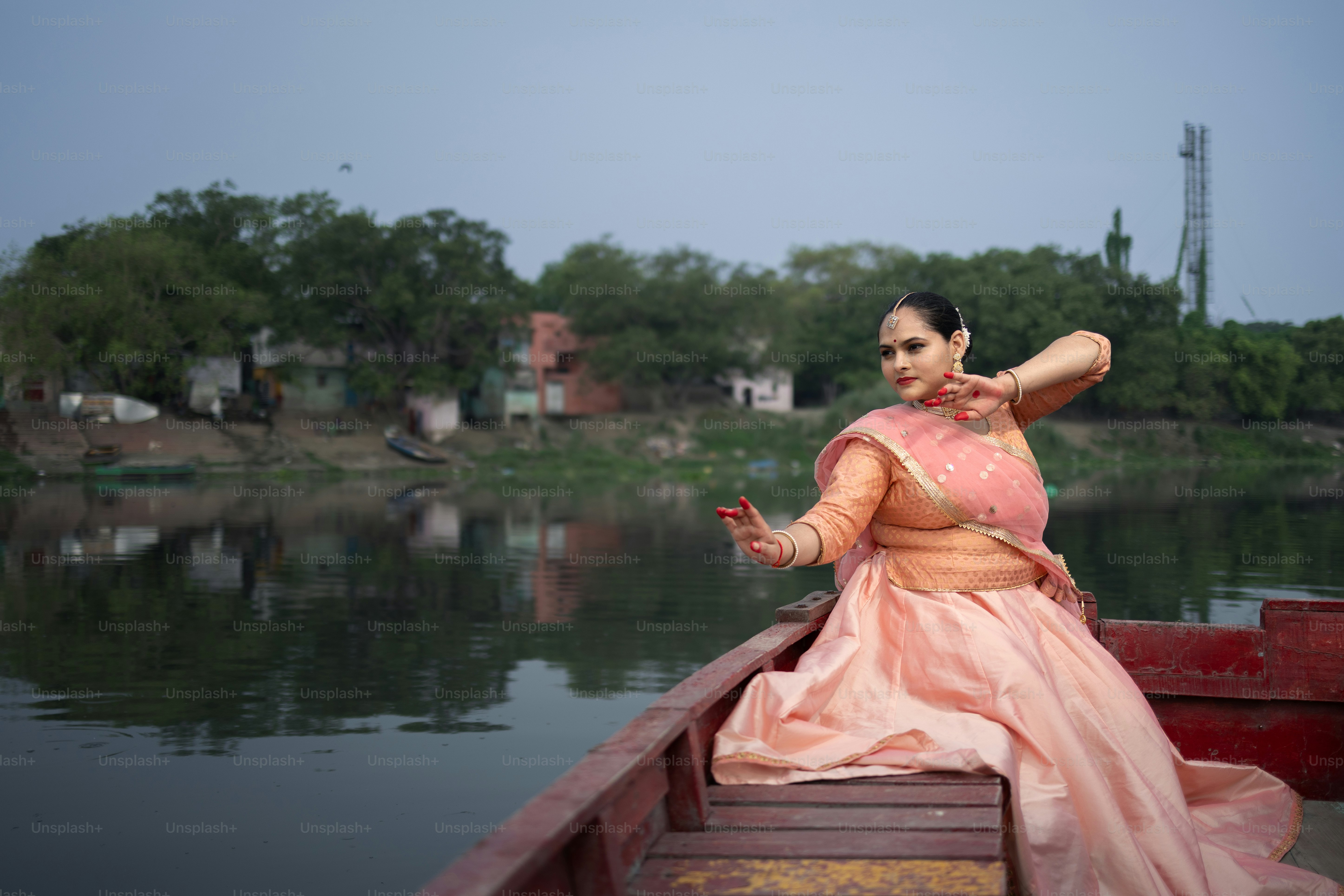 A woman in a pink dress sitting in a boat