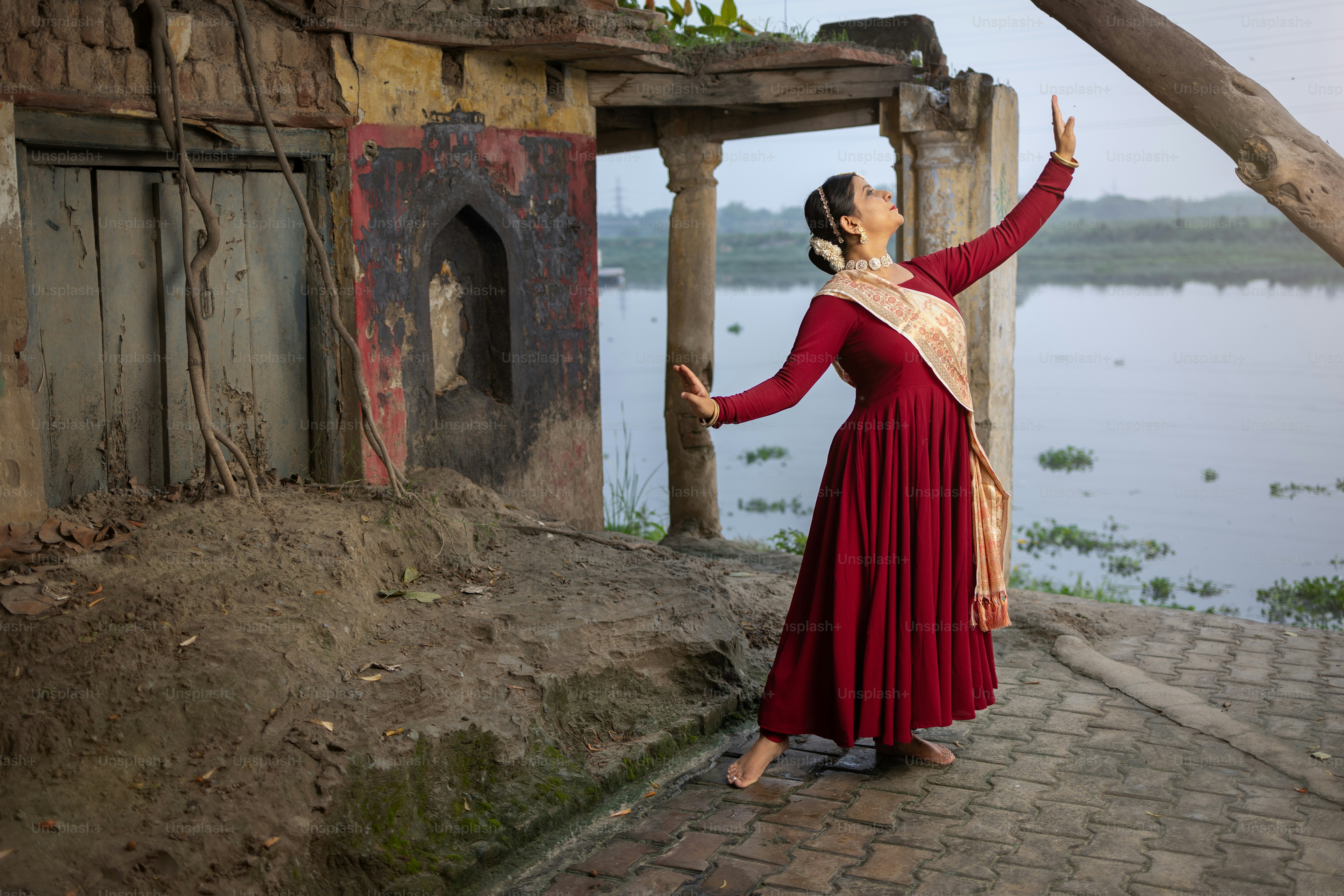 Une femme en robe rouge debout au bord d’un lac