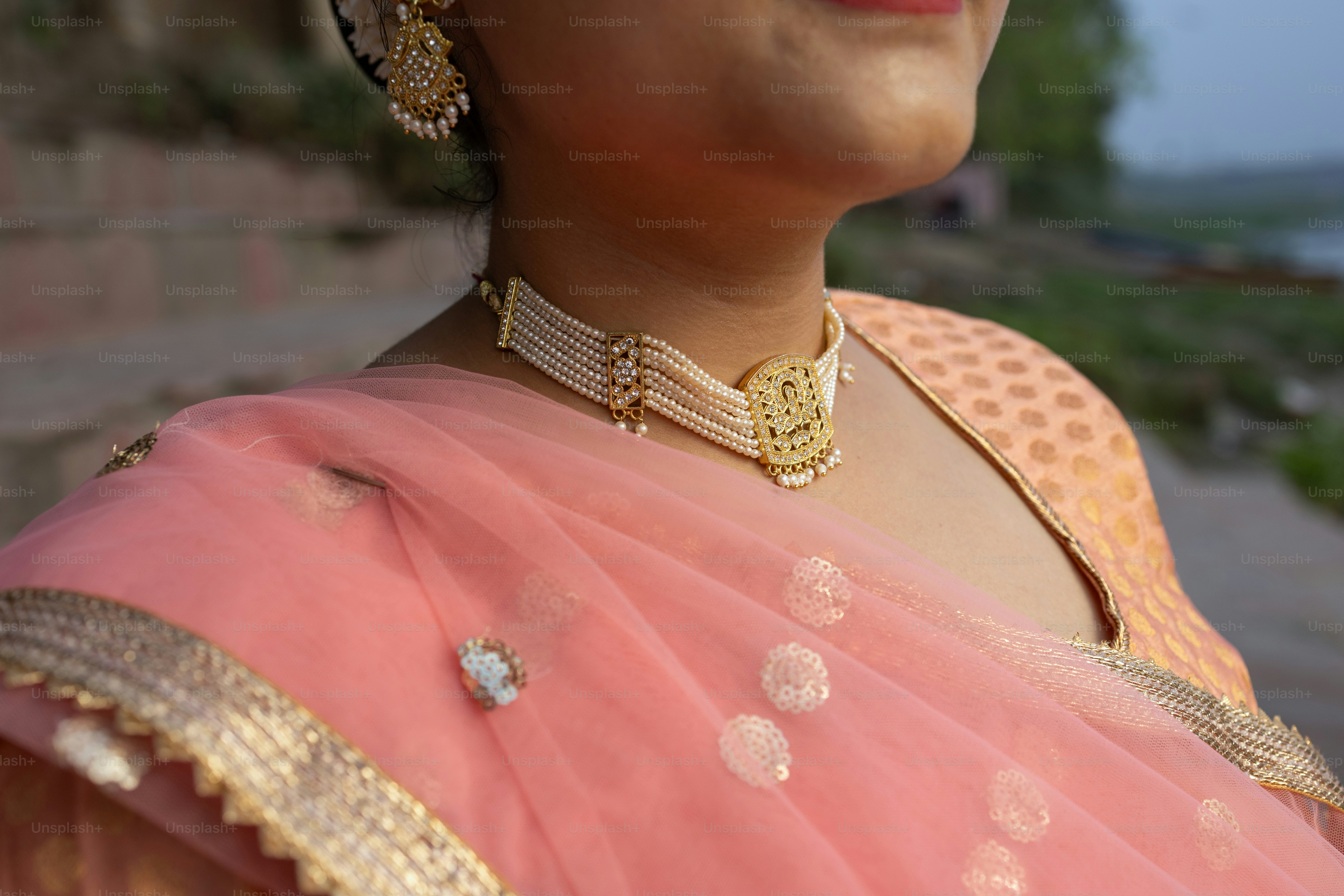 A woman wearing a pink sari and gold jewelry