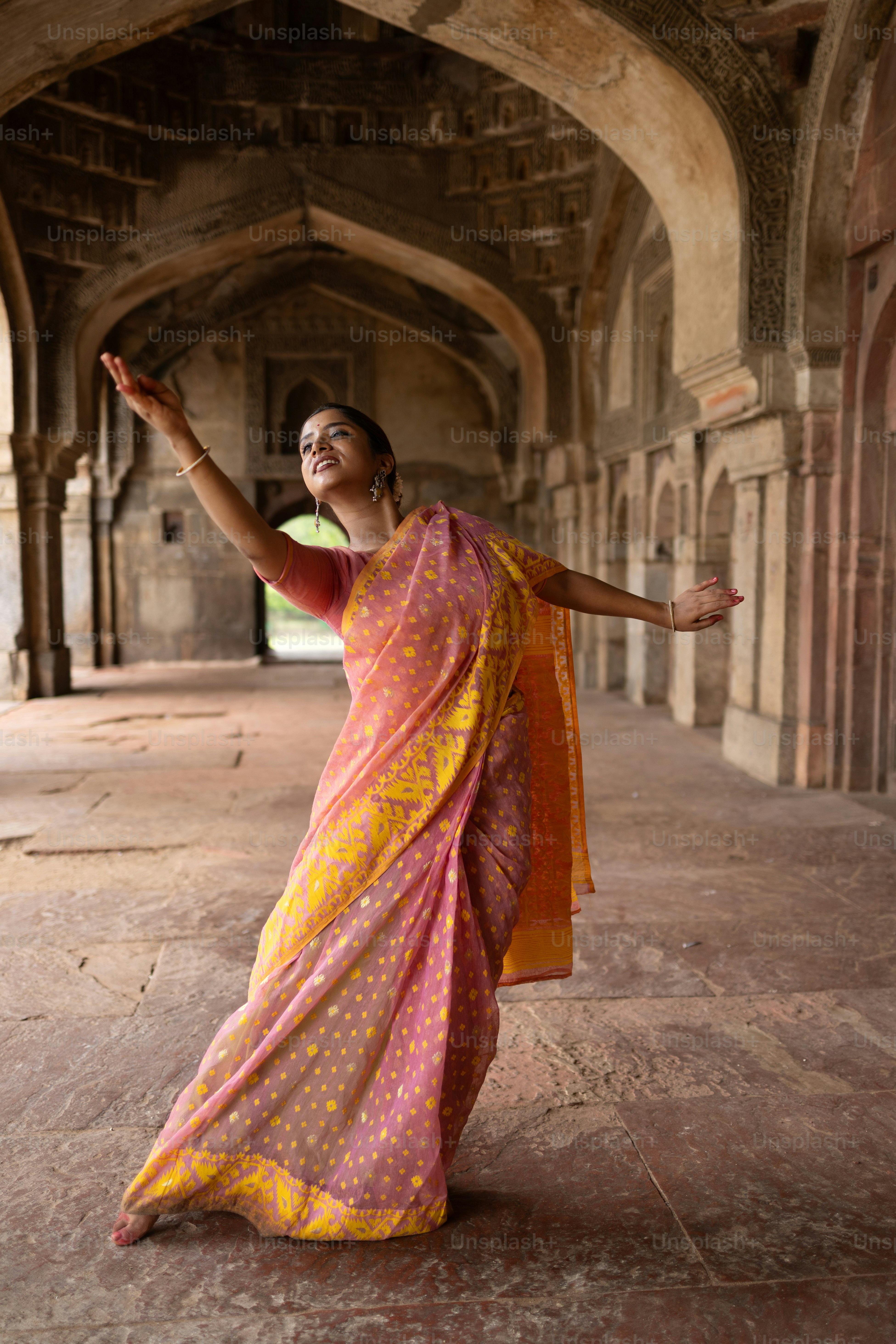 Une femme en sari jaune et rose dansant