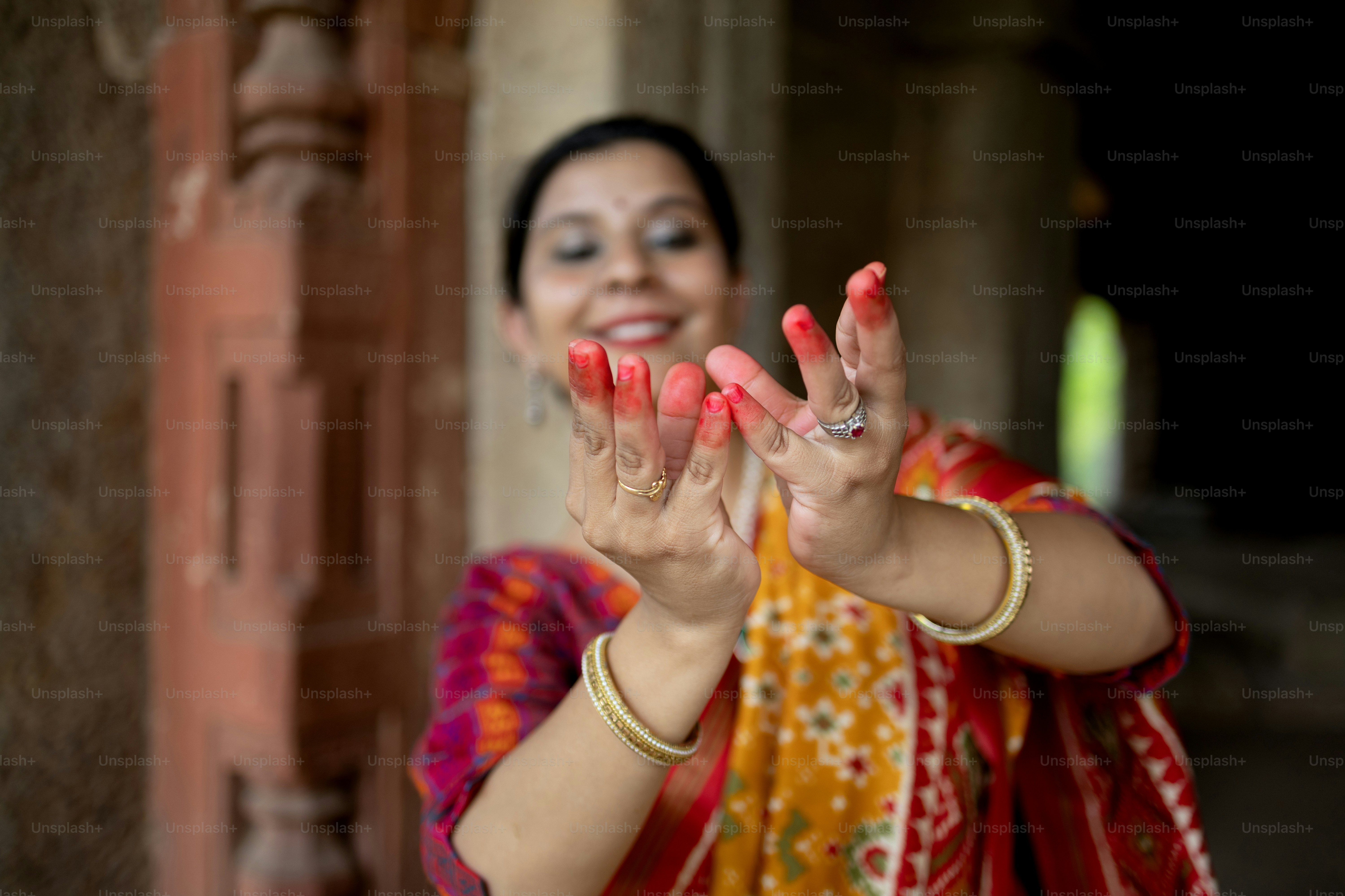 A woman in a colorful sari holding her hands up