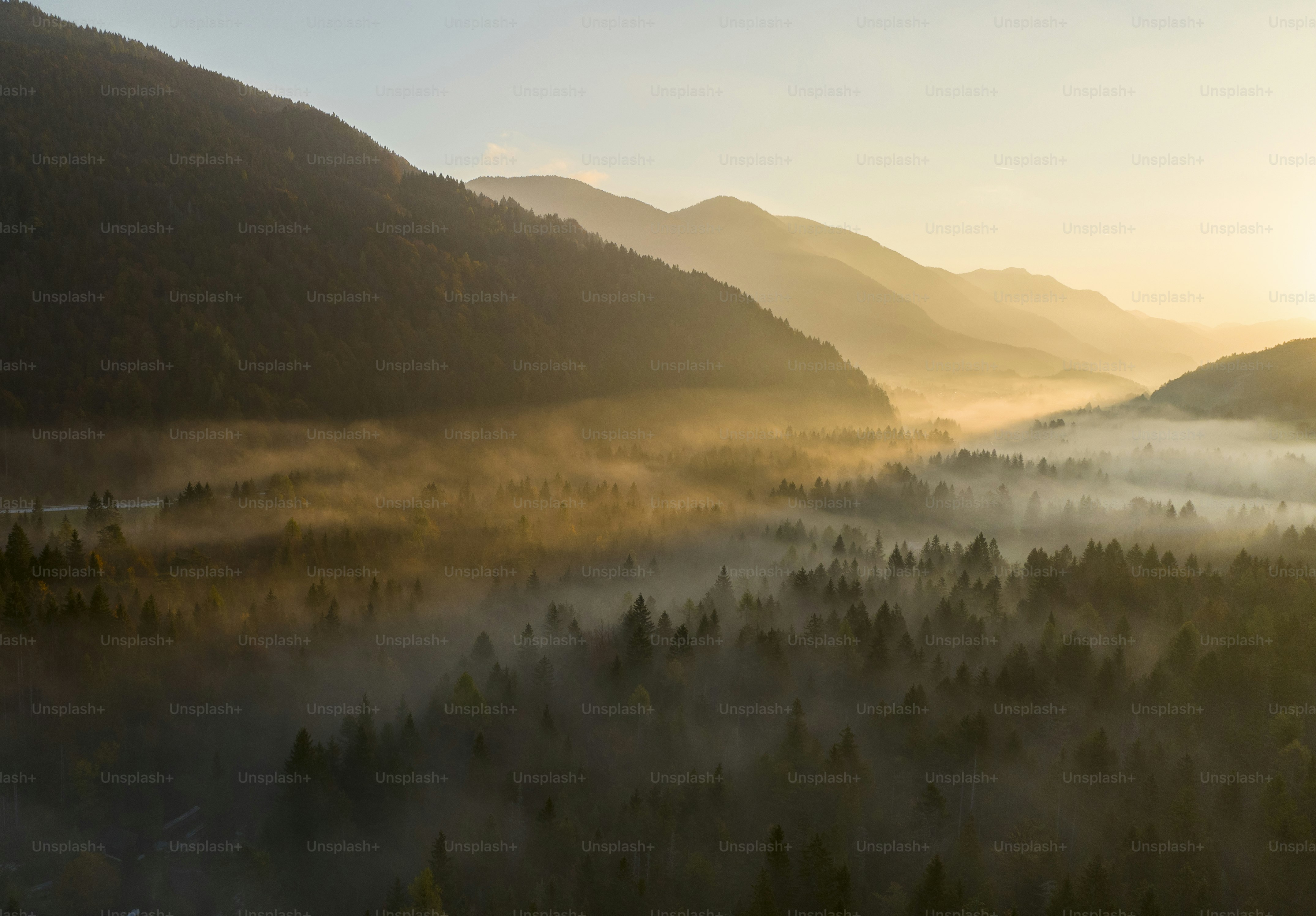 The sun is setting over a valley with mountains in the background