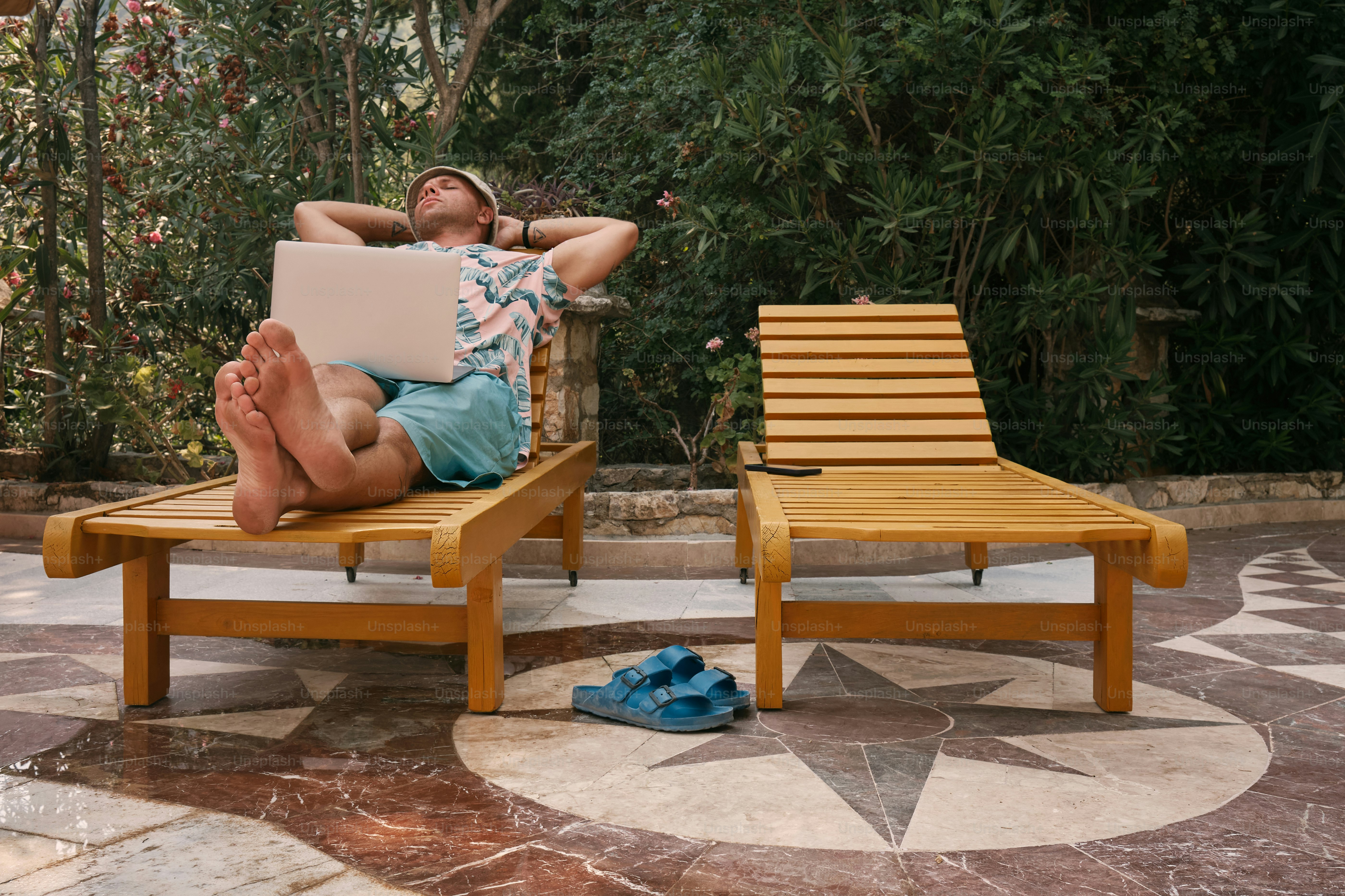 Un hombre sentado en una silla con una computadora portátil en su regazo