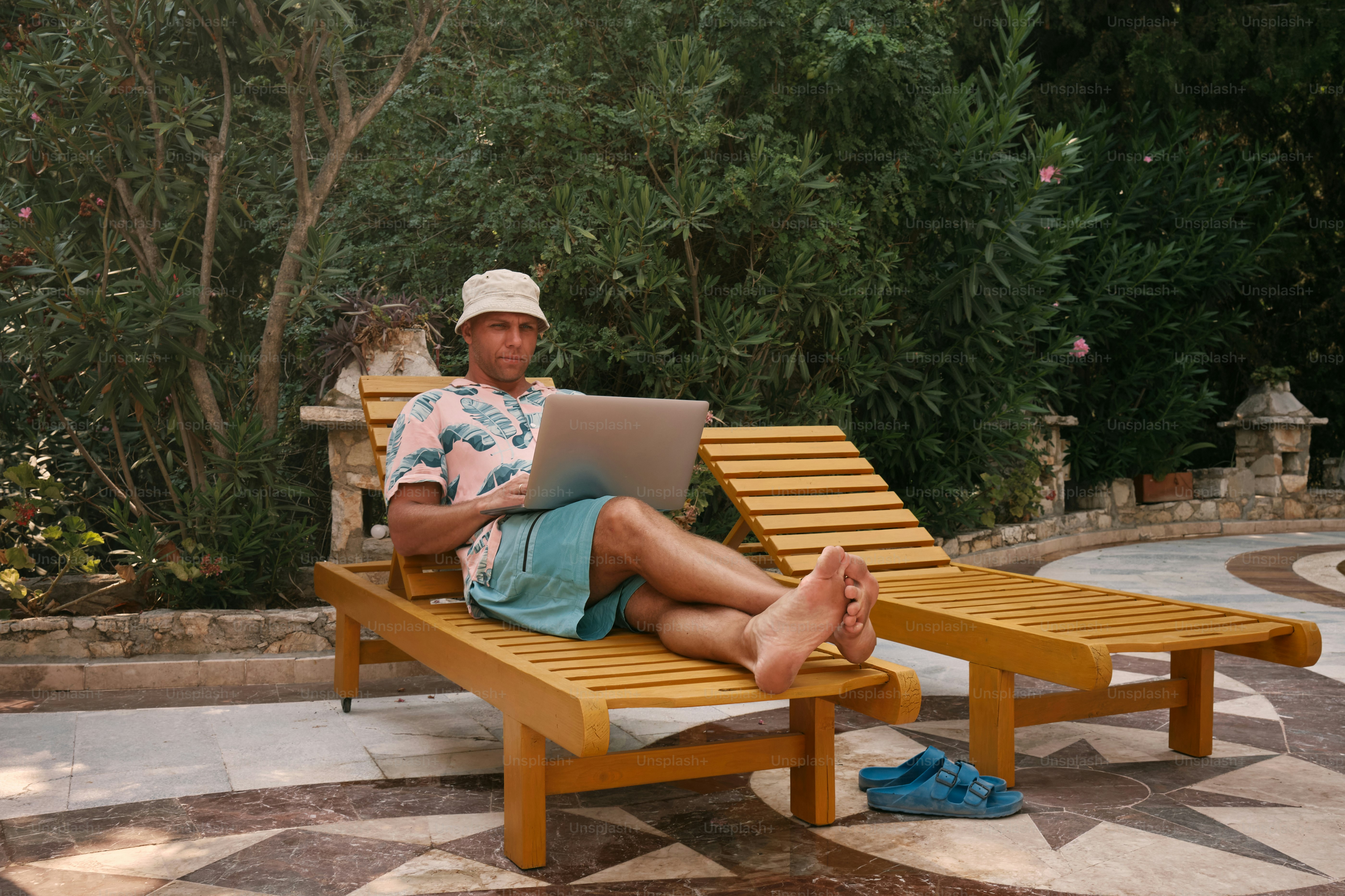 A man sitting on a wooden bench using a laptop