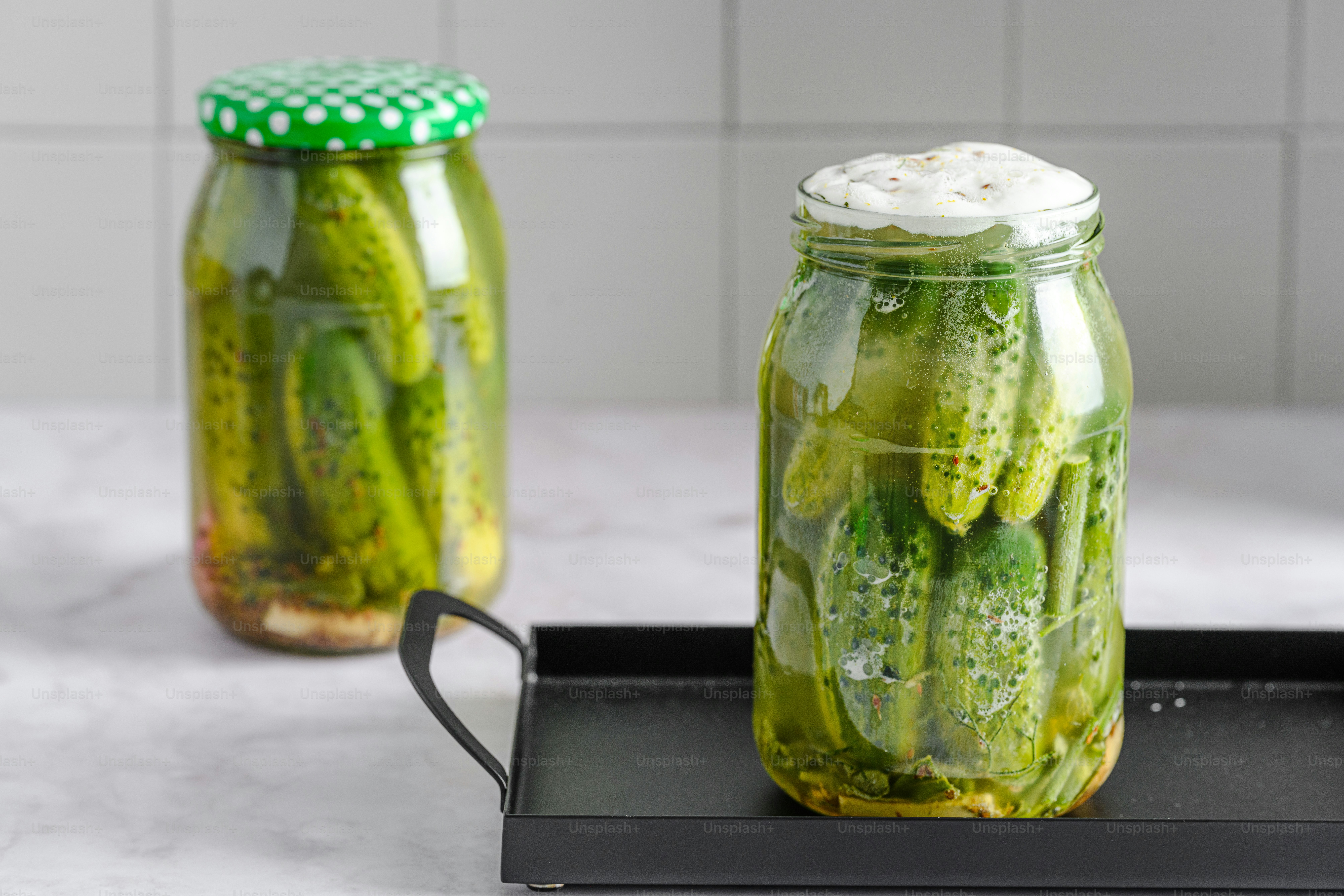 Zwei Gläser mit Gurken auf einem Tablett