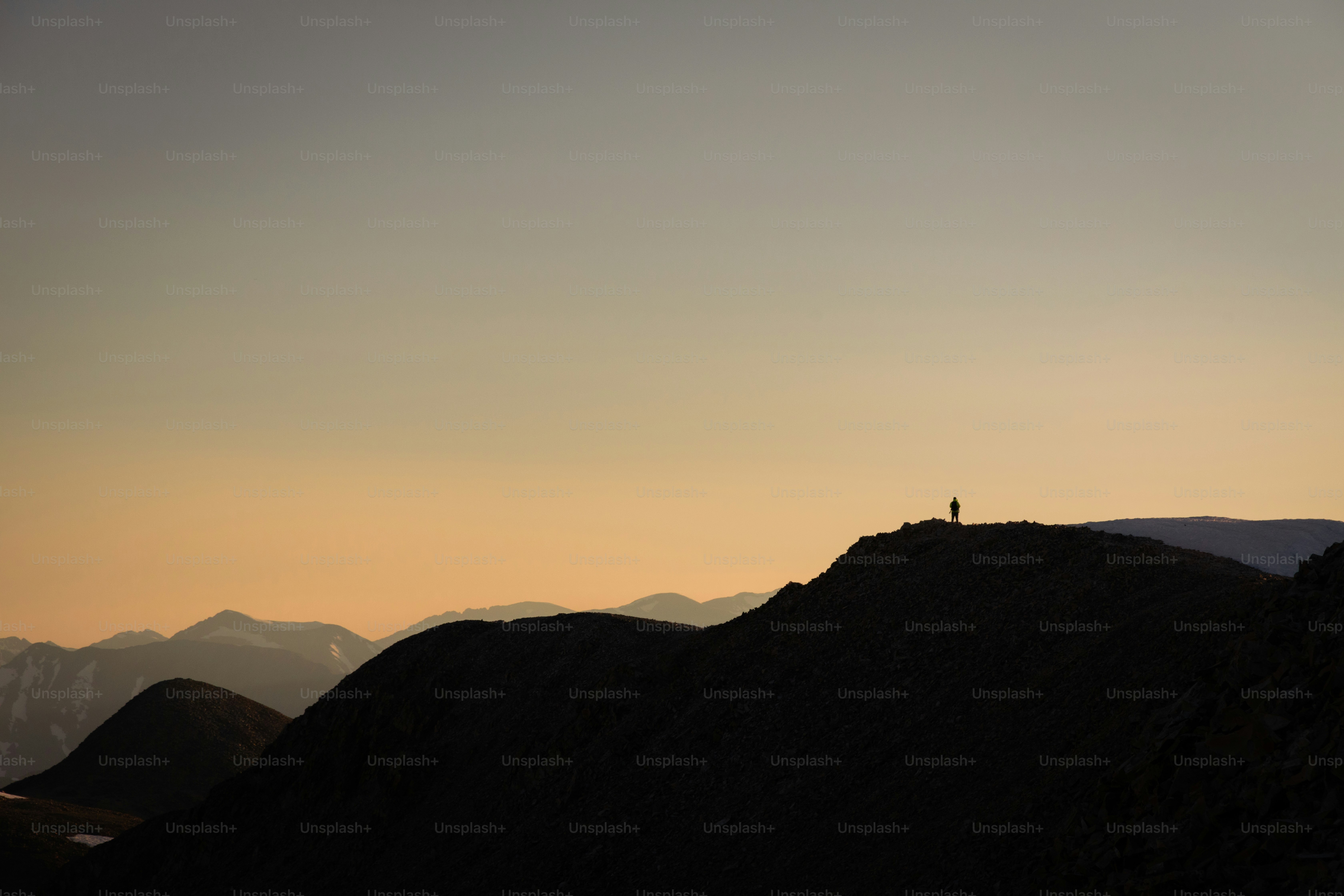 A person standing on top of a mountain at sunset