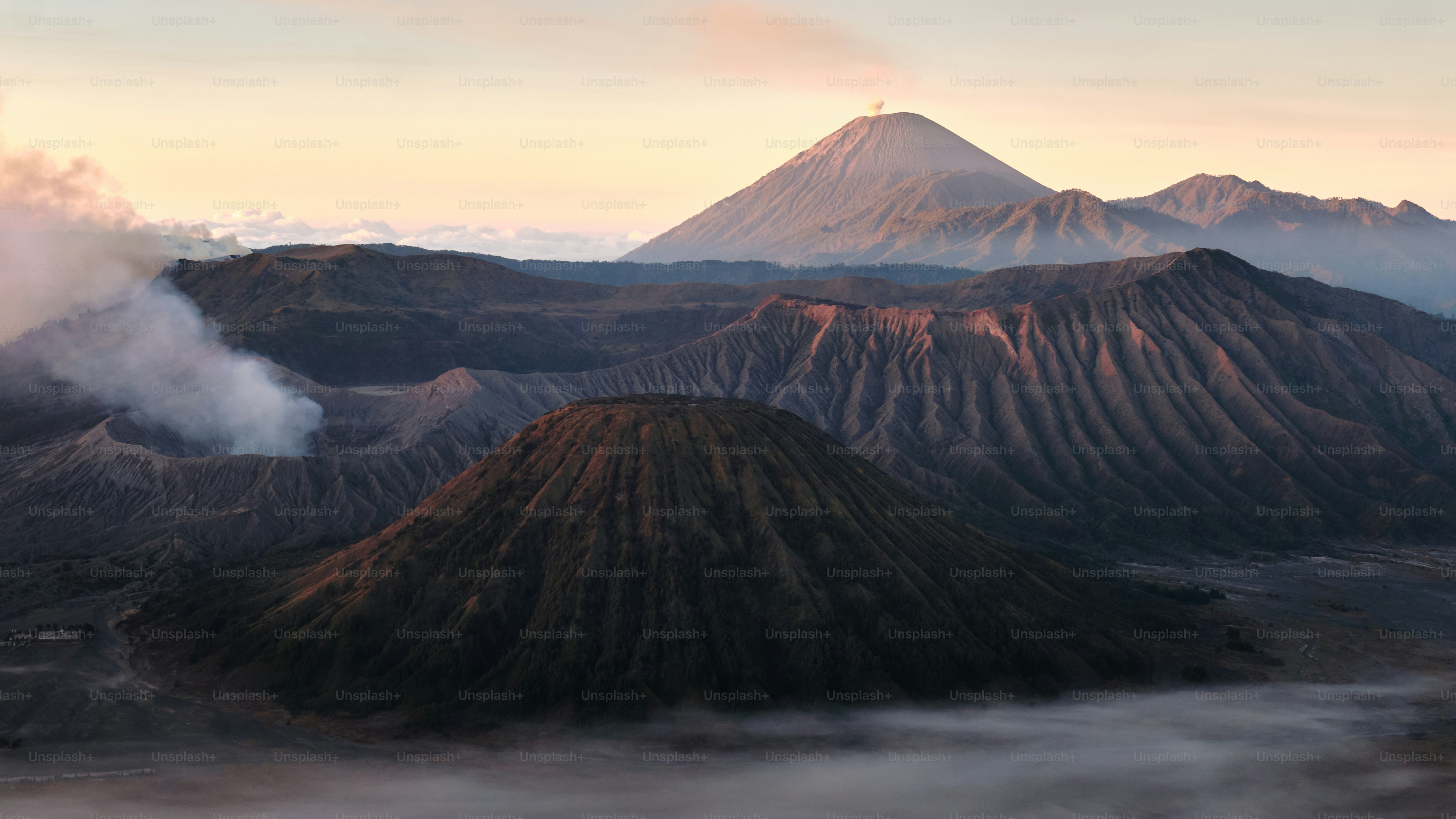 A large plume of smoke rising from the top of a mountain