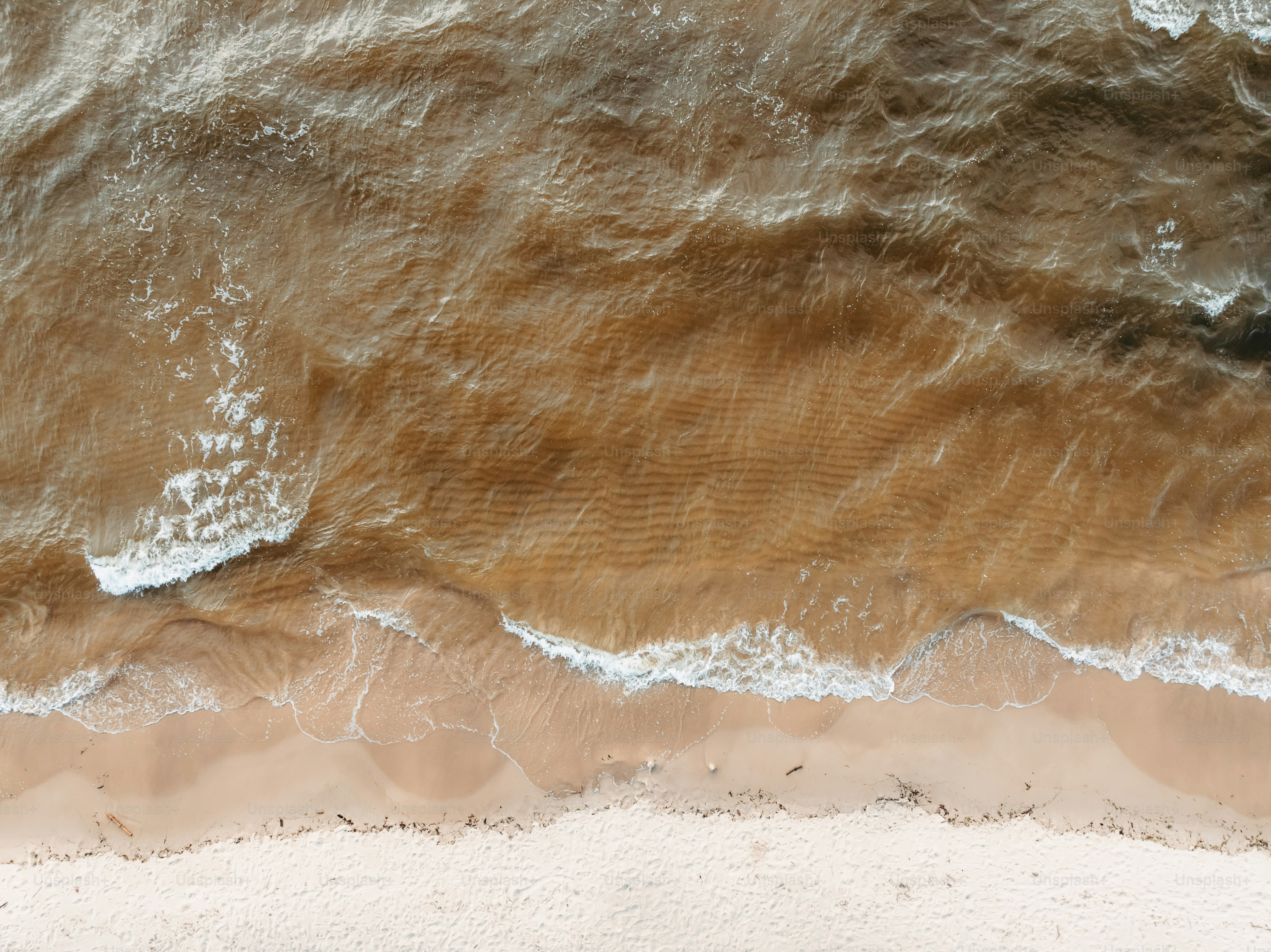 An aerial view of a sandy beach with waves