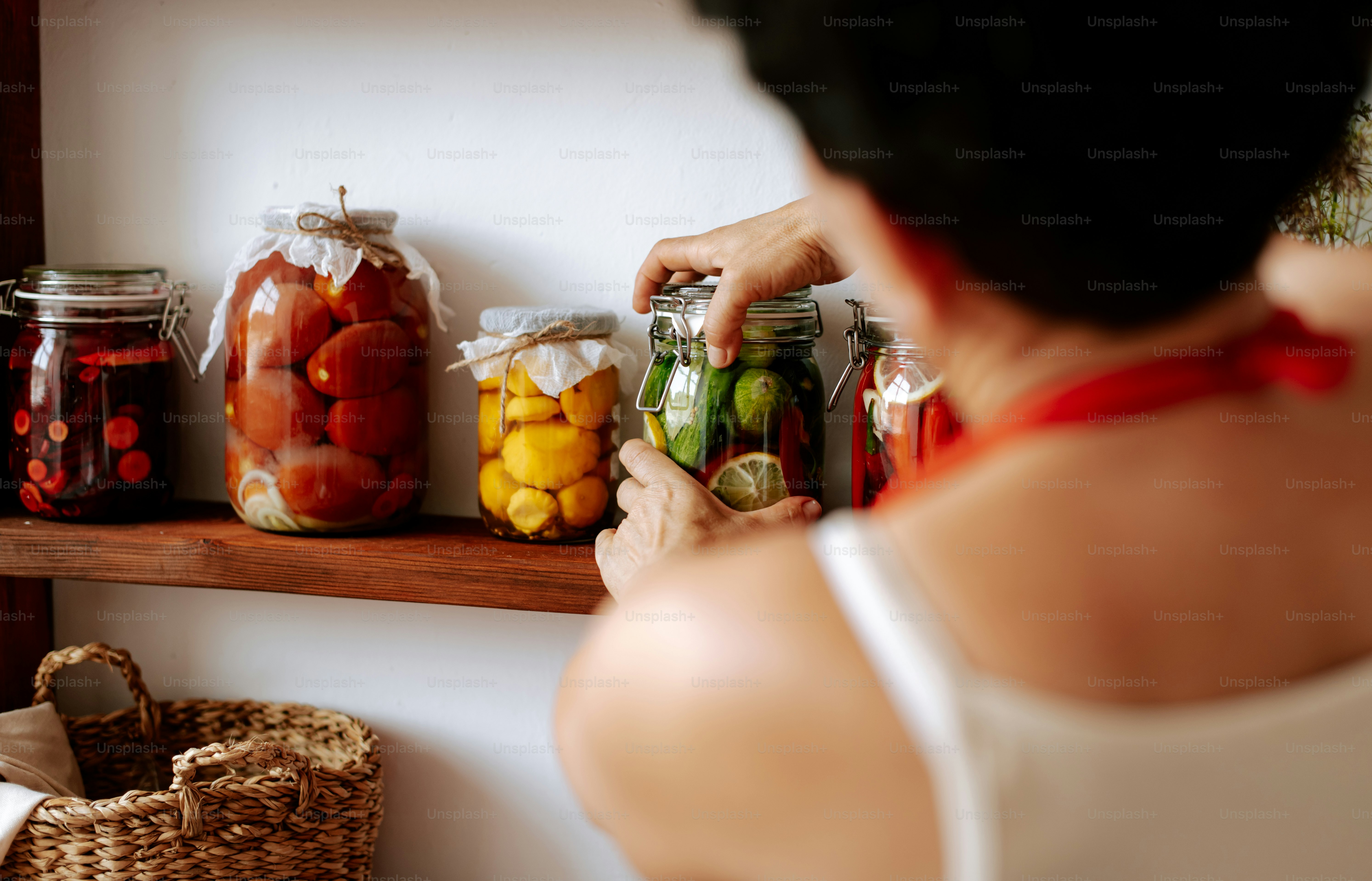 Uma mulher em pé na frente de uma prateleira cheia de potes de comida