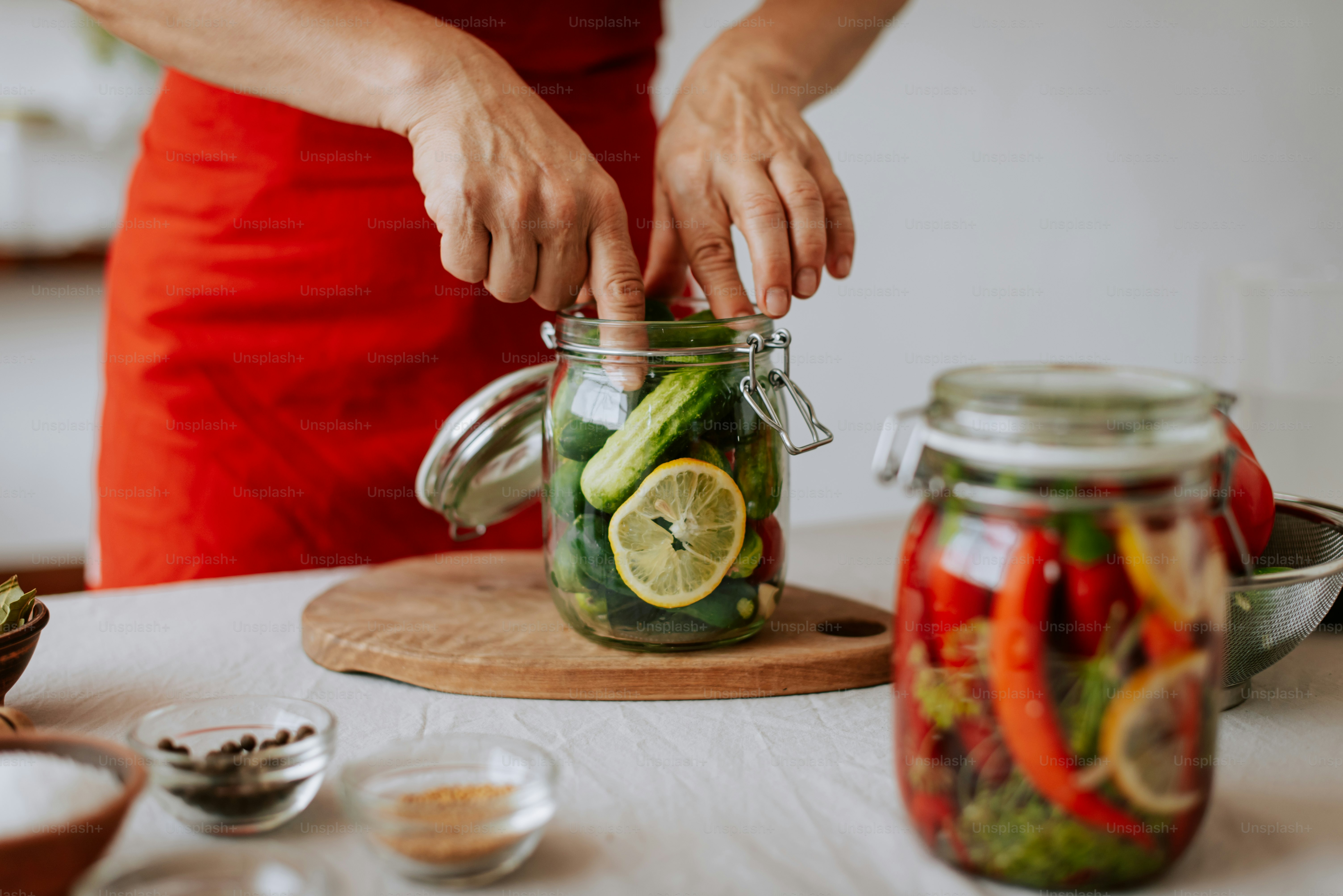Eine Frau in einem roten Kleid füllt Gurken in ein Glas