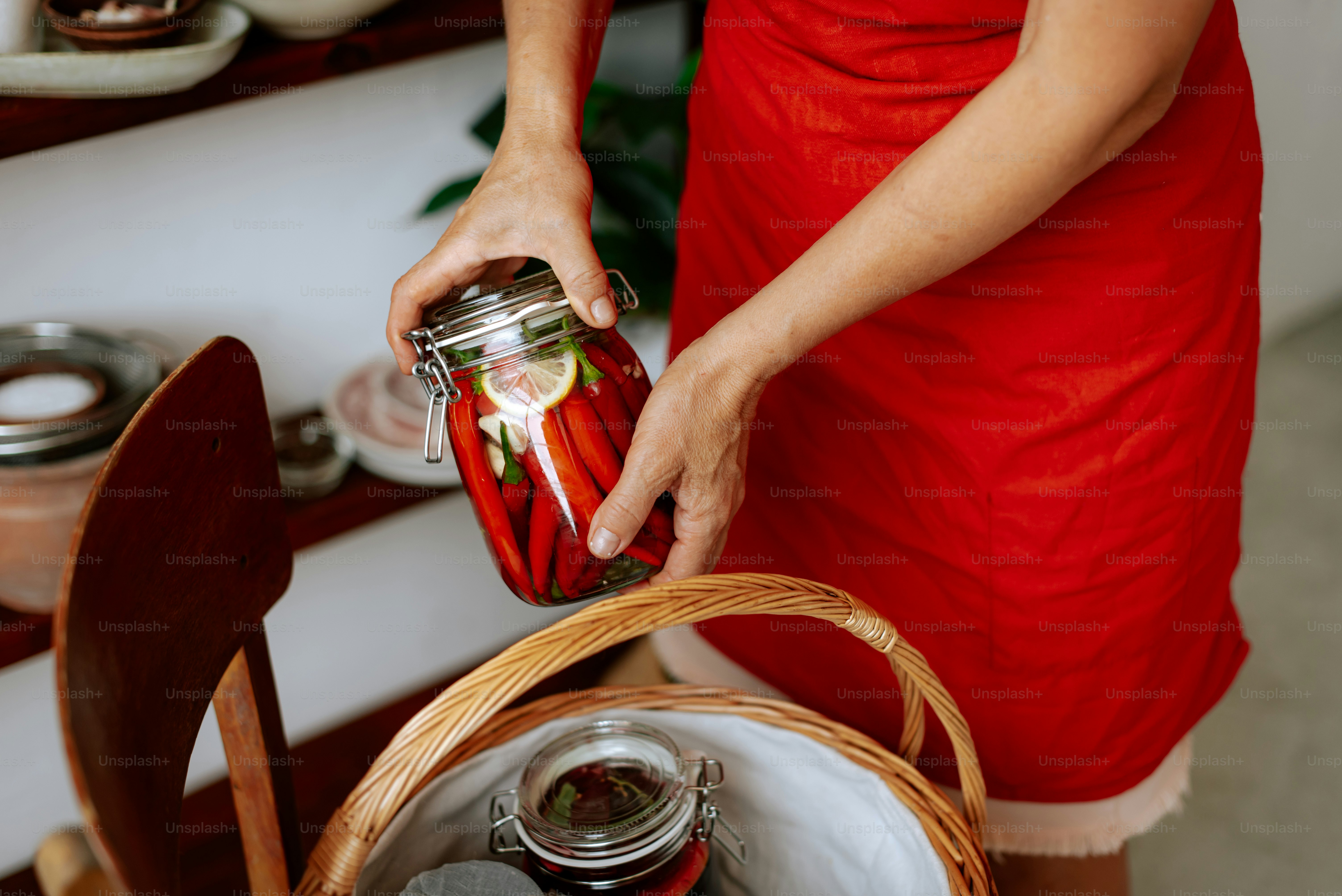 A woman in a red dress holding a jar of food photo – Fermented foods ...