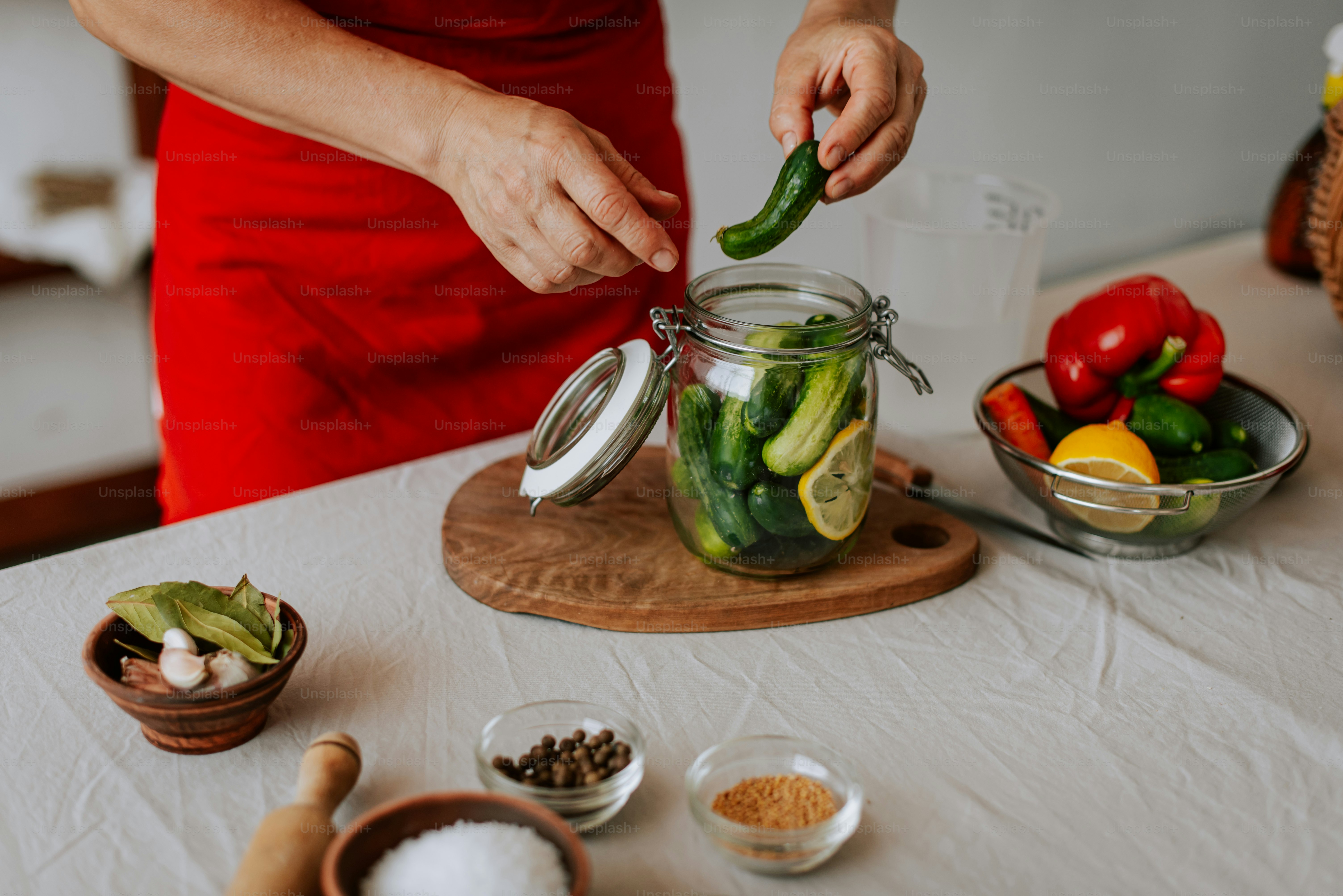 Eine Frau in einem roten Kleid bereitet ein Glas Gurken vor