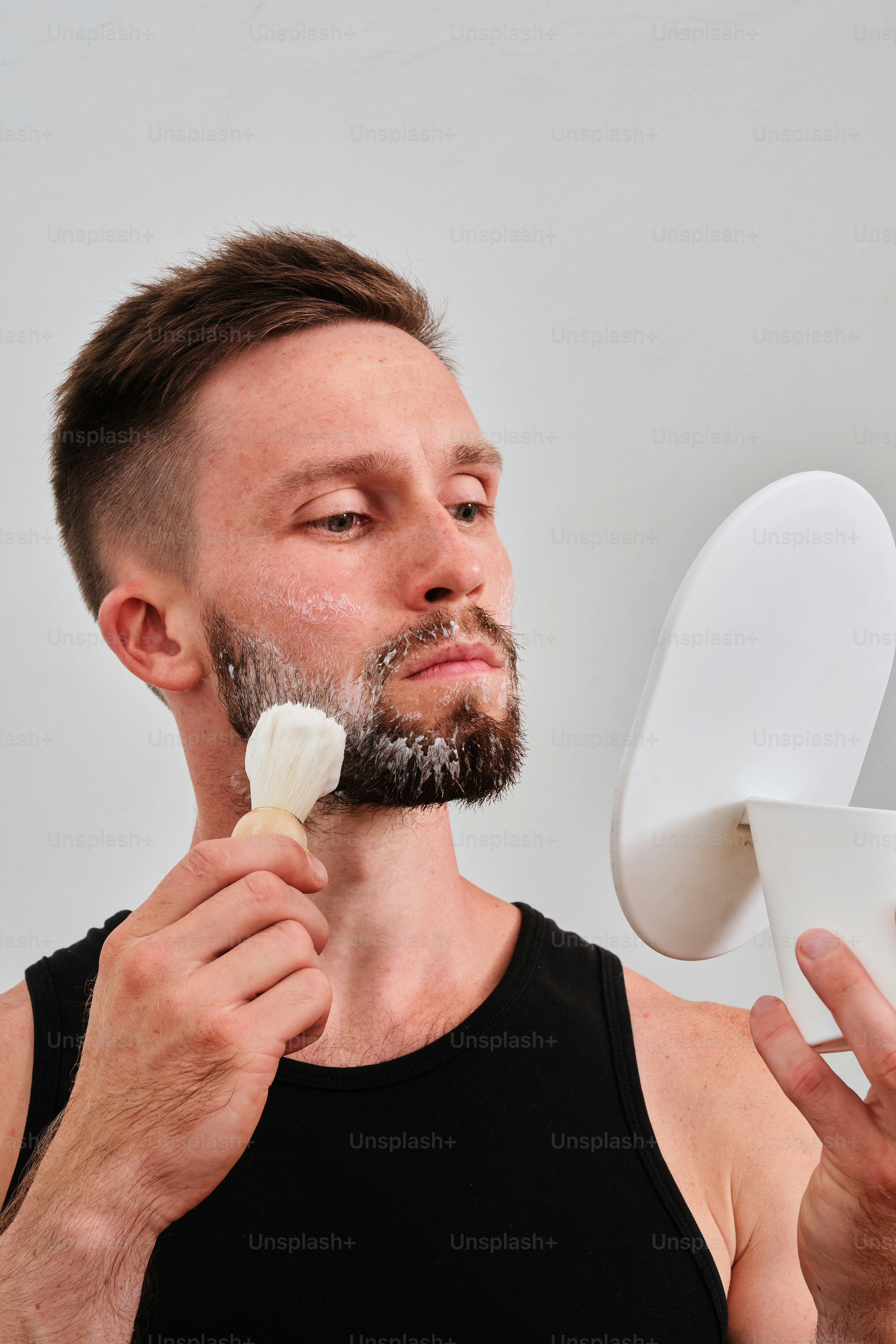 A man is shaving his face with a razor photo – Facial procedures Image ...