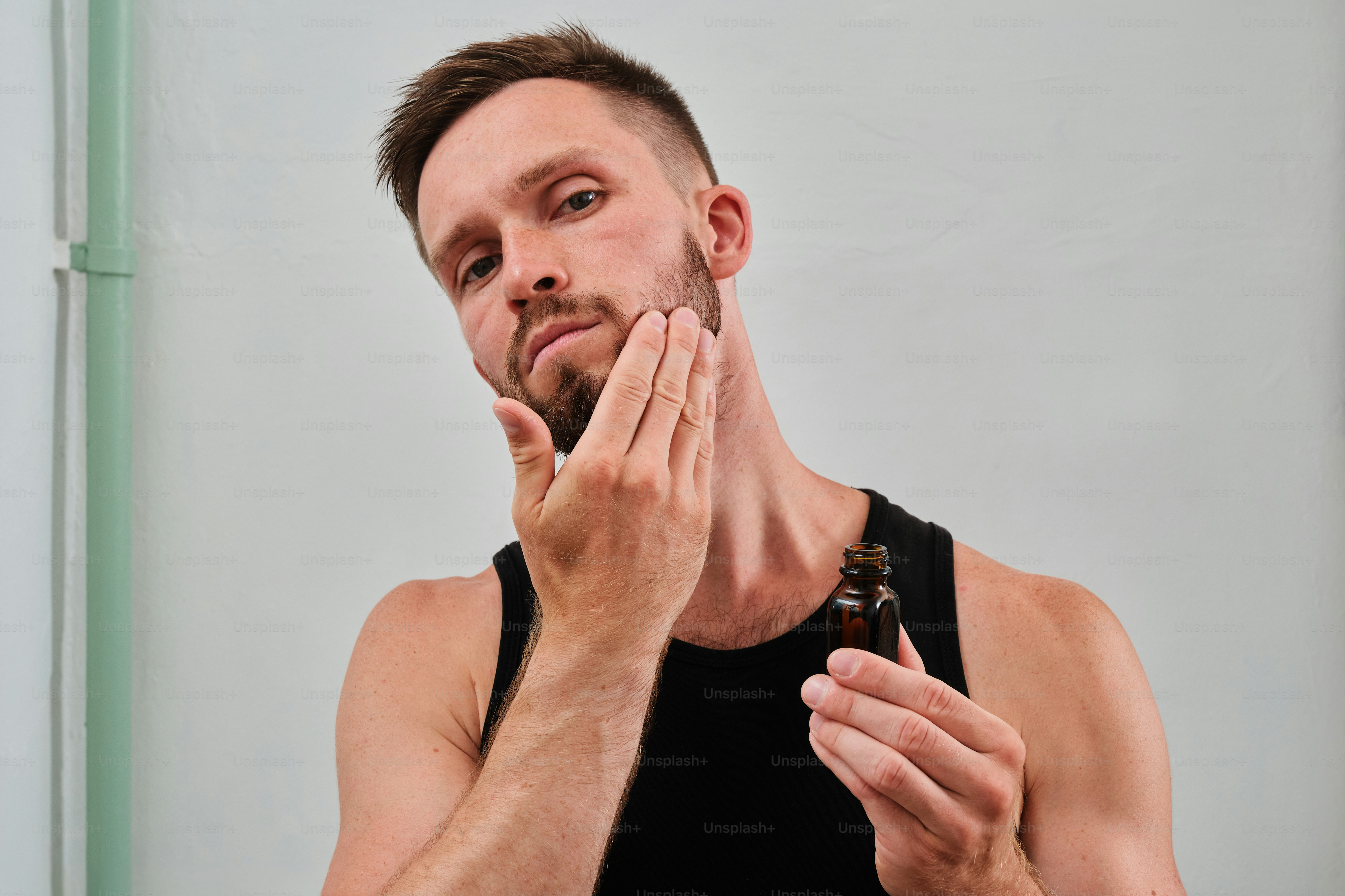 A man standing in front of a mirror holding his hand to his face