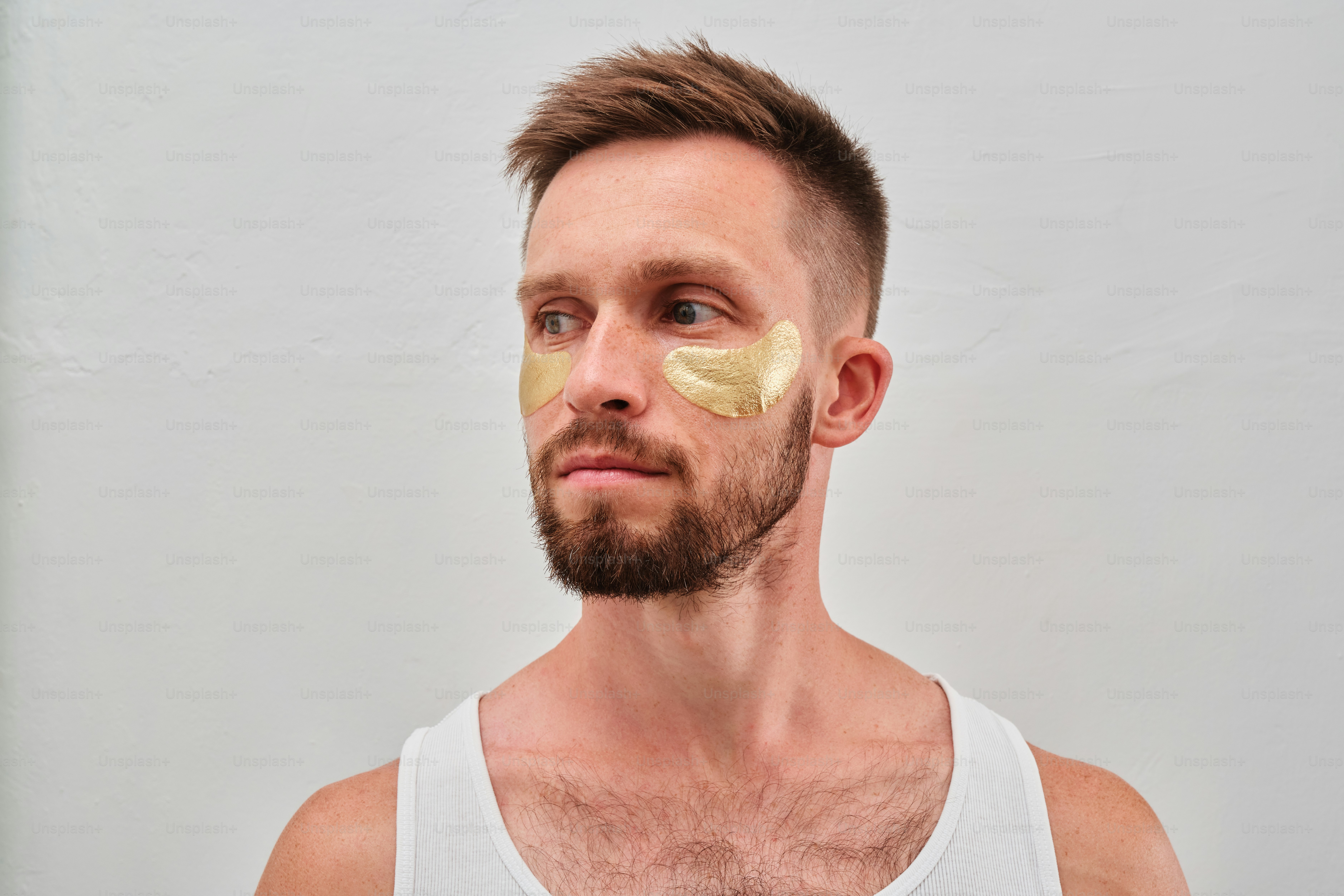 Un homme portant un débardeur blanc et une feuille d’or sur le visage