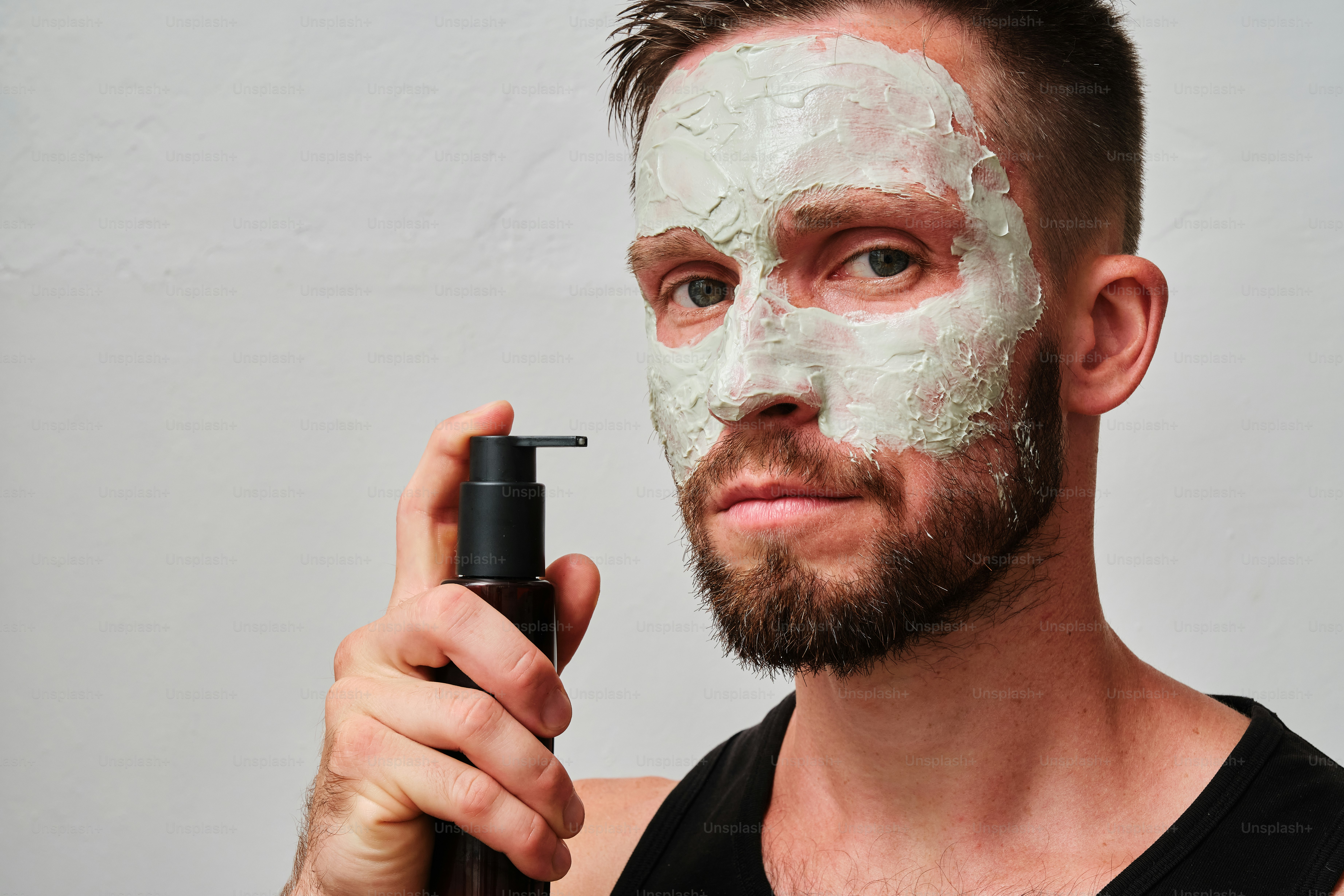 A man with a facial mask on holding a bottle