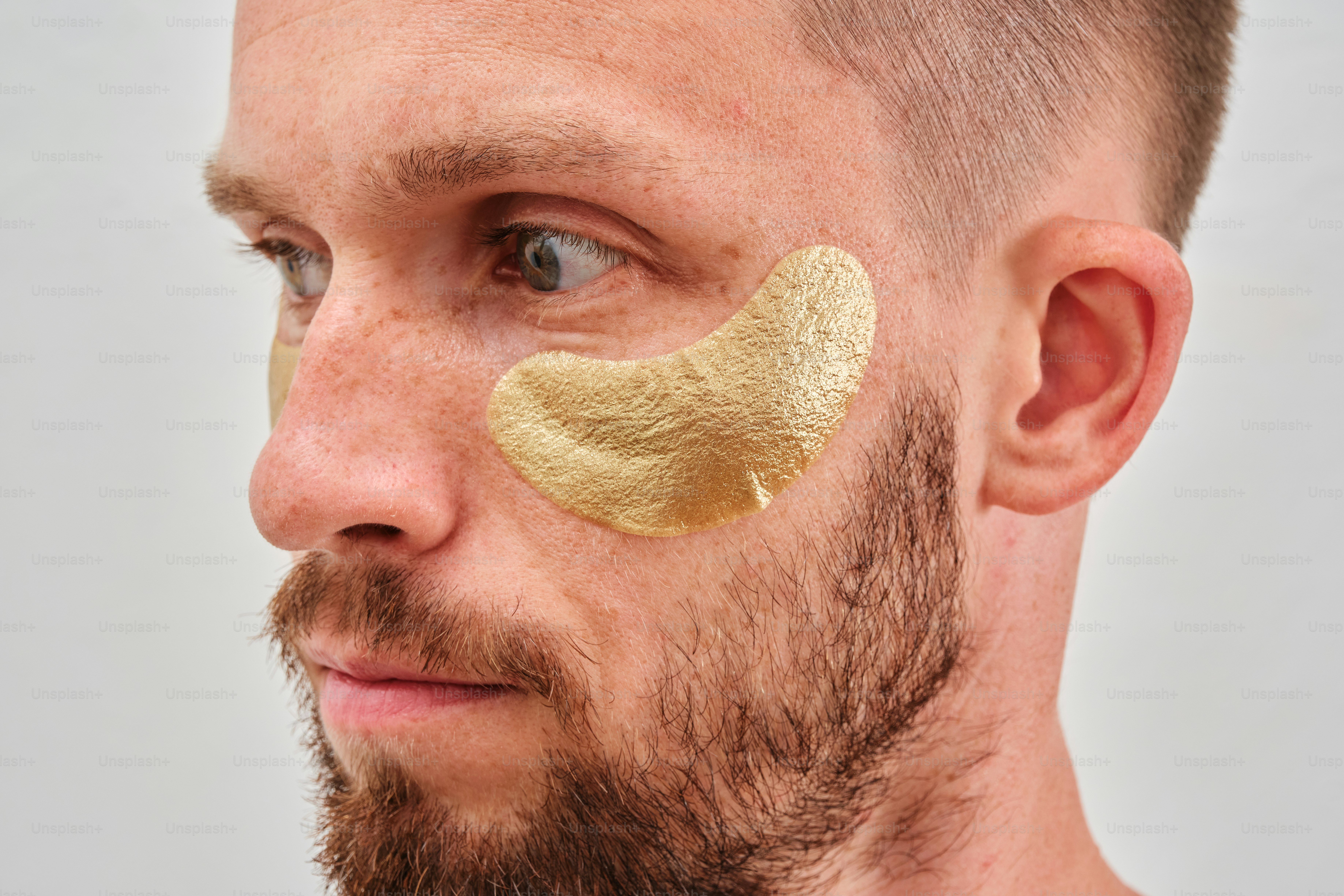 A man with a beard and a gold mask on his face