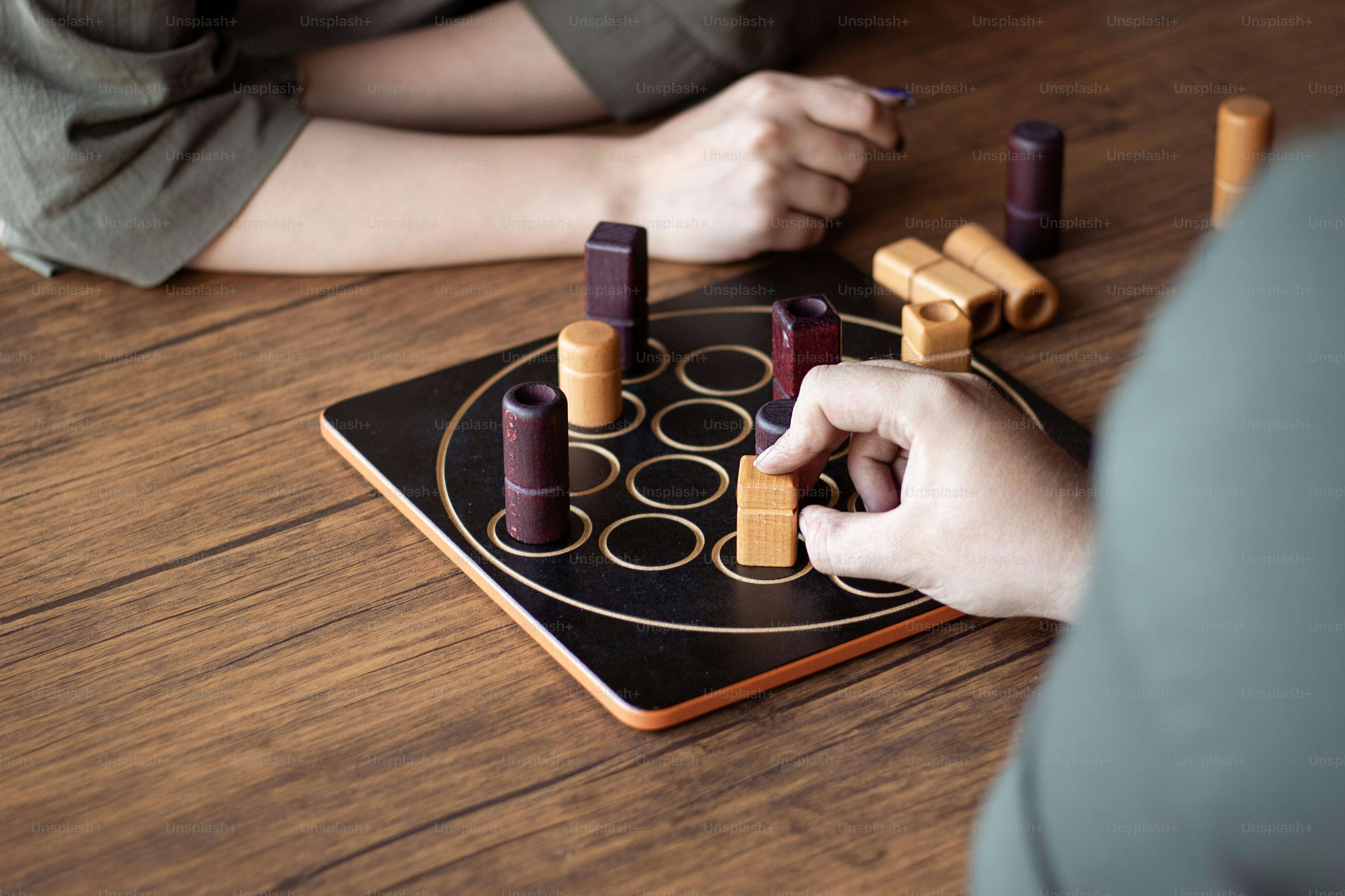 Two people playing a game of dominos on a wooden table