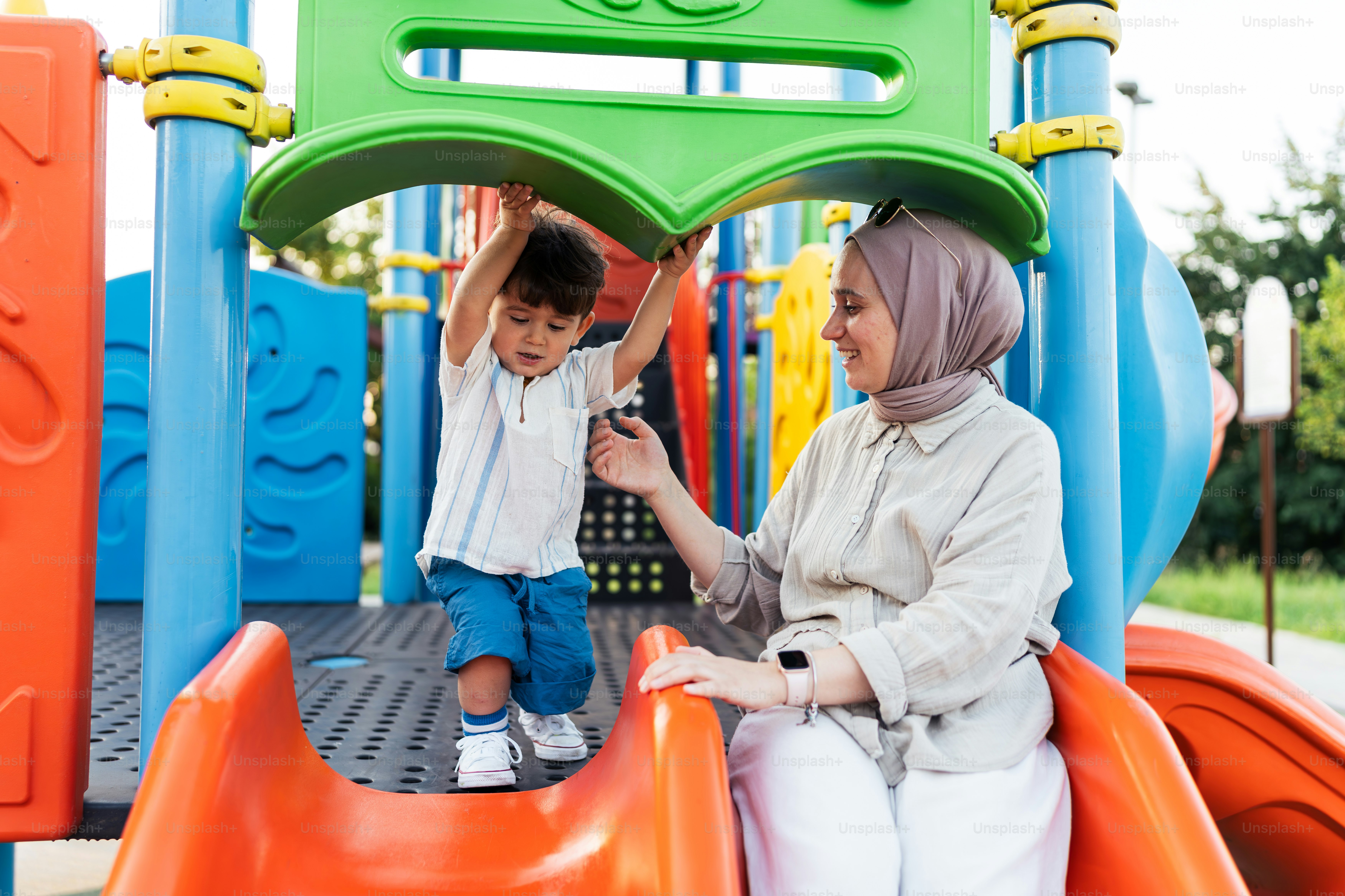 Seorang wanita dan seorang anak bermain di taman bermain