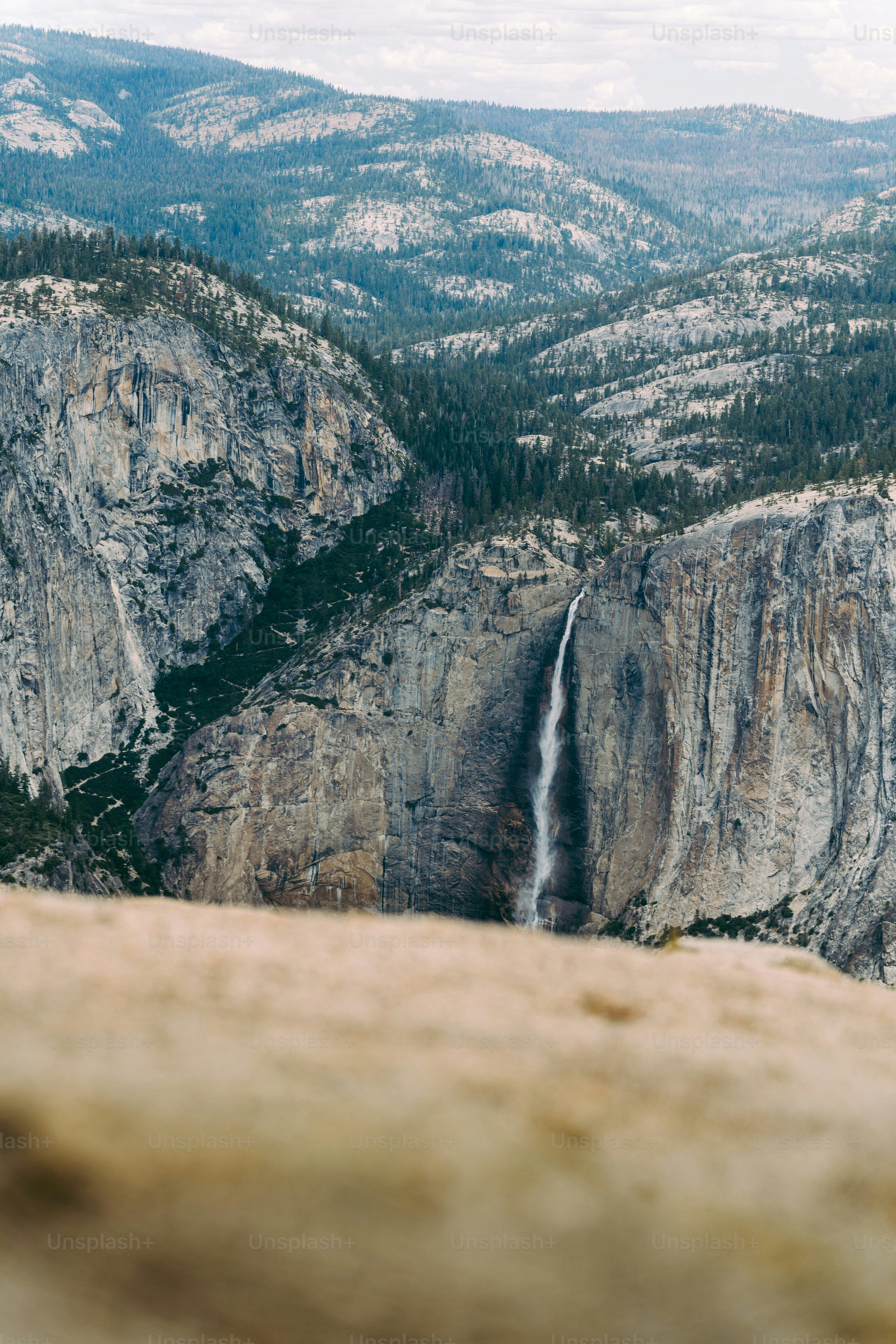 A man standing on top of a cliff next to a waterfall