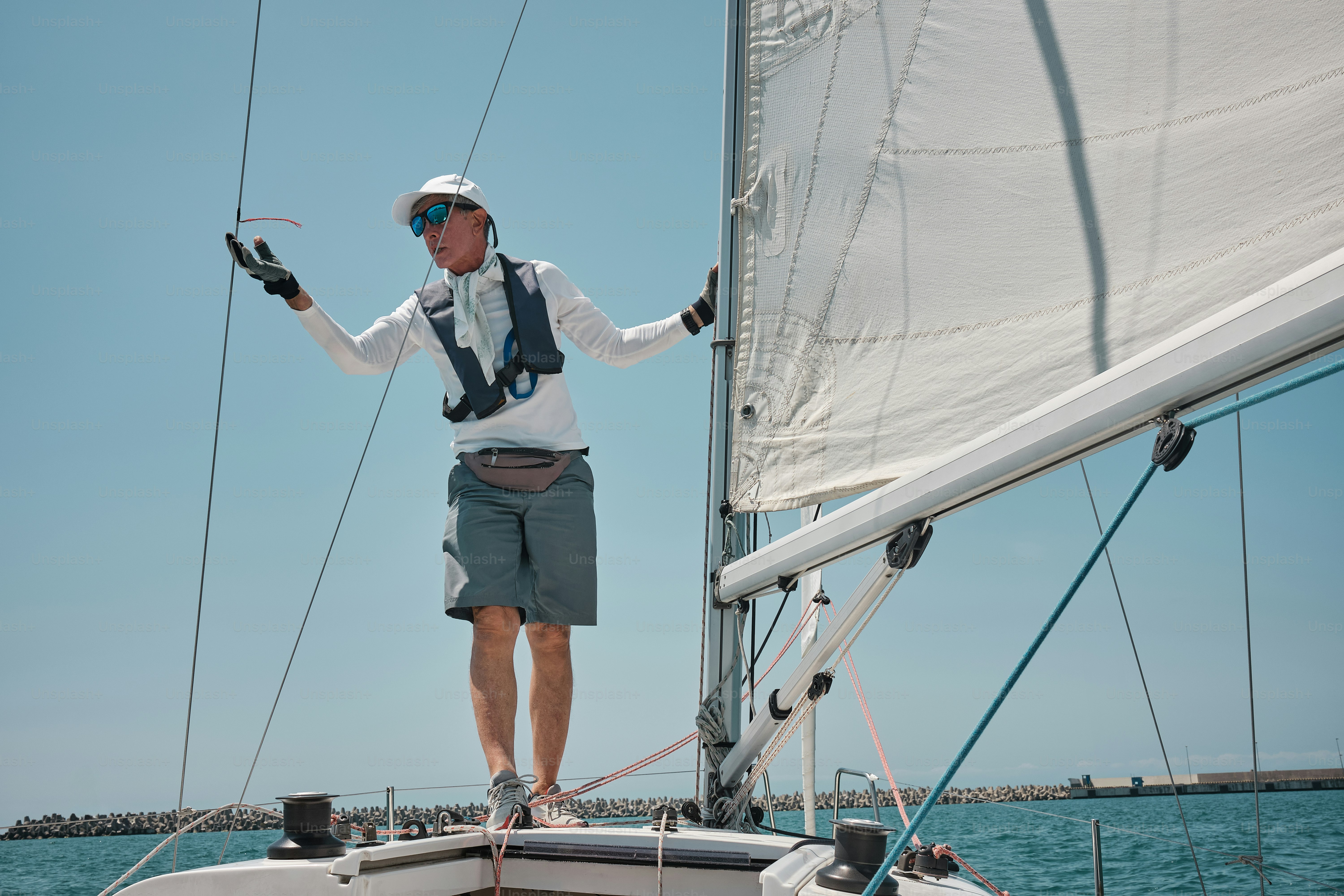 A man standing on top of a sailboat in the ocean