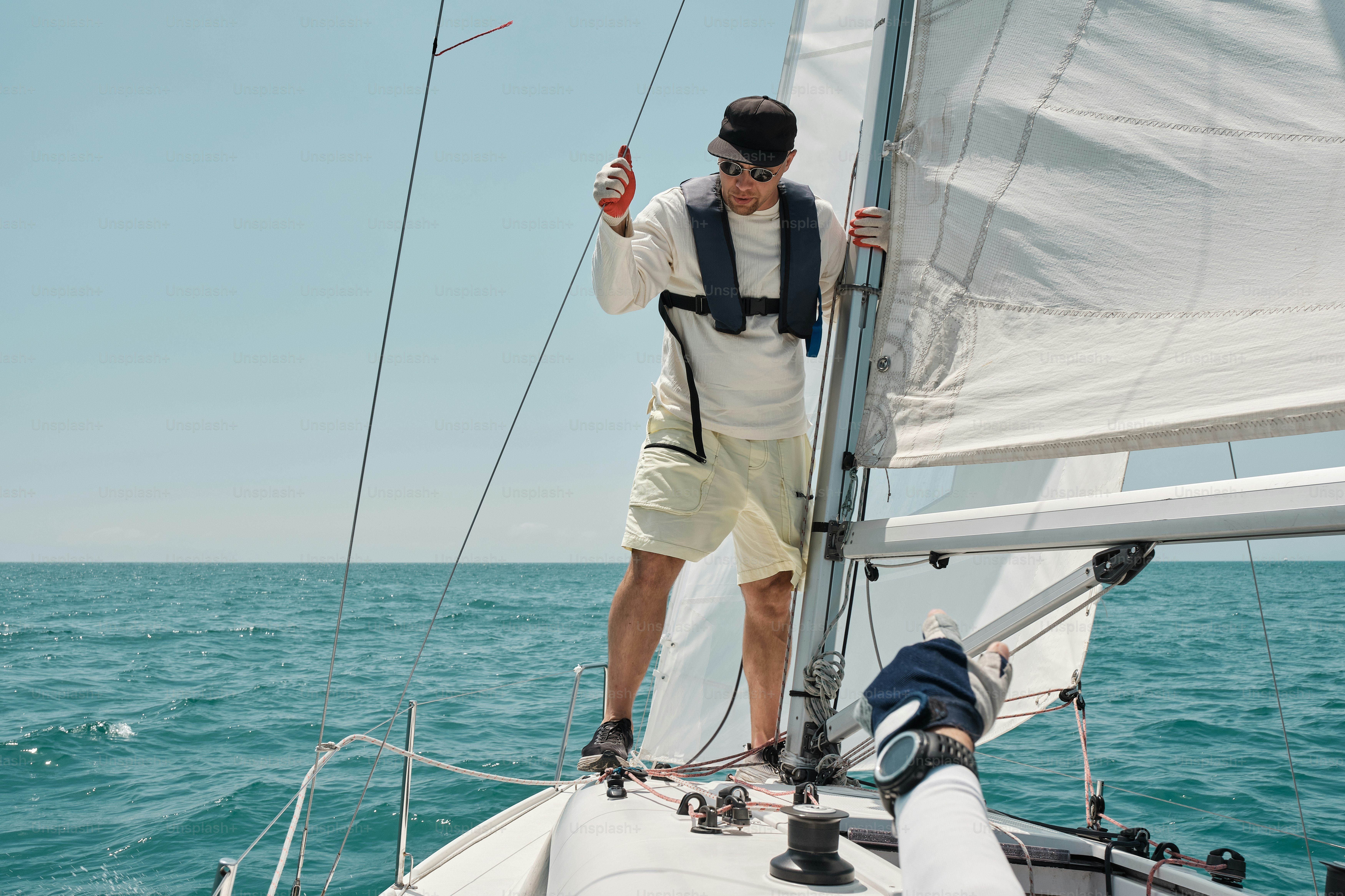 A man standing on the front of a sailboat