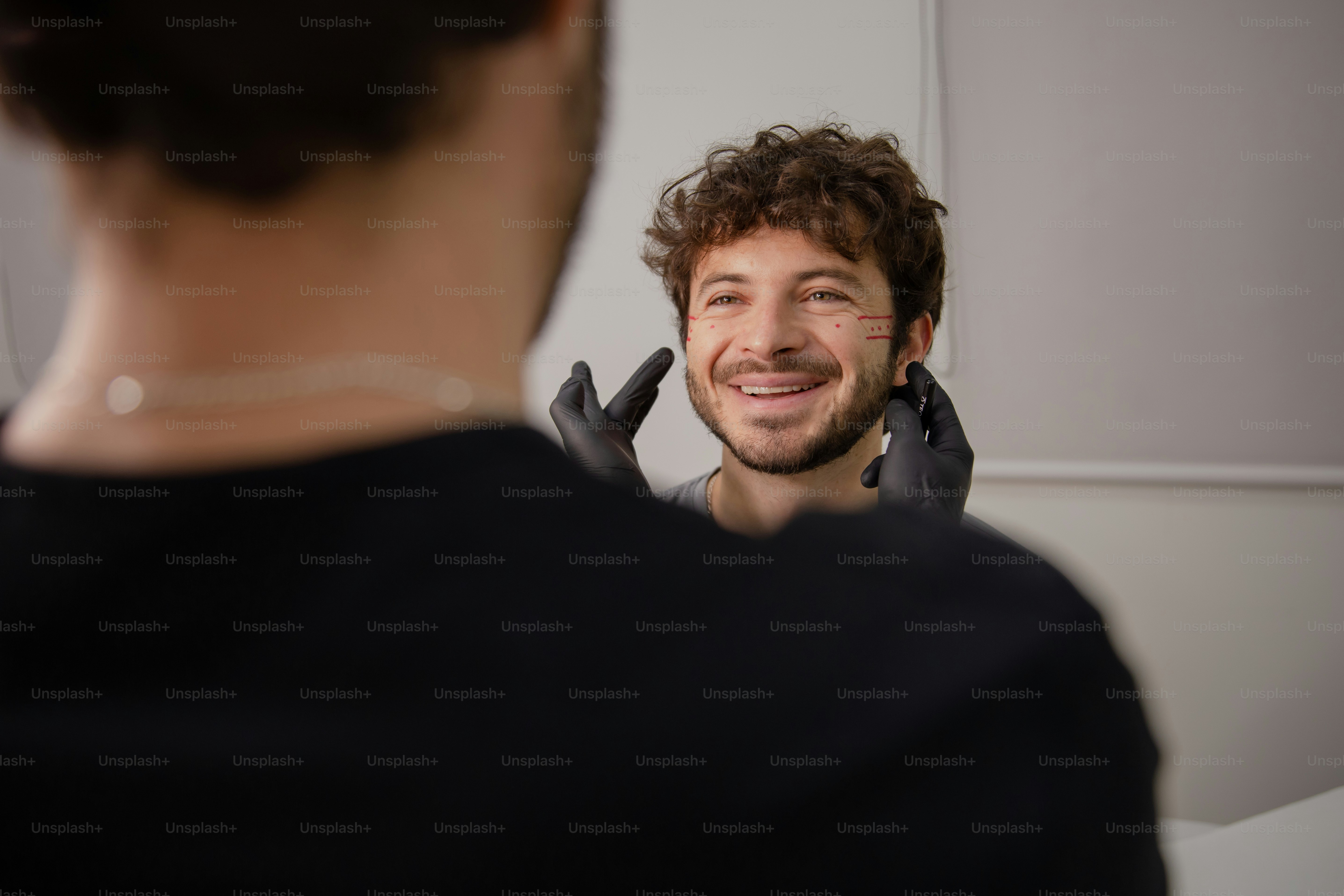 A man in a black shirt is smiling and talking on a cell phone