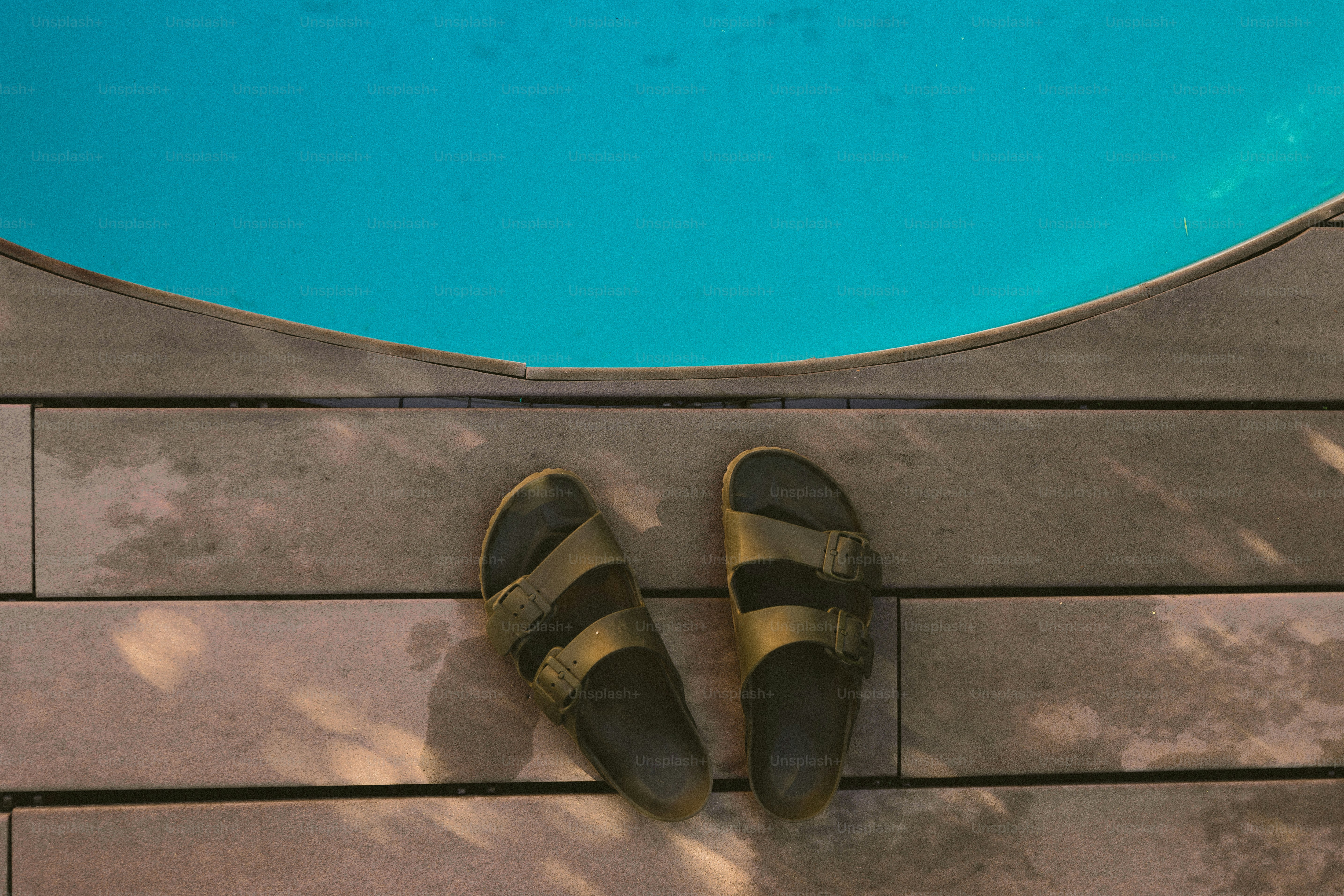 Une paire de chaussures posée sur un plancher en bois à côté d’une piscine