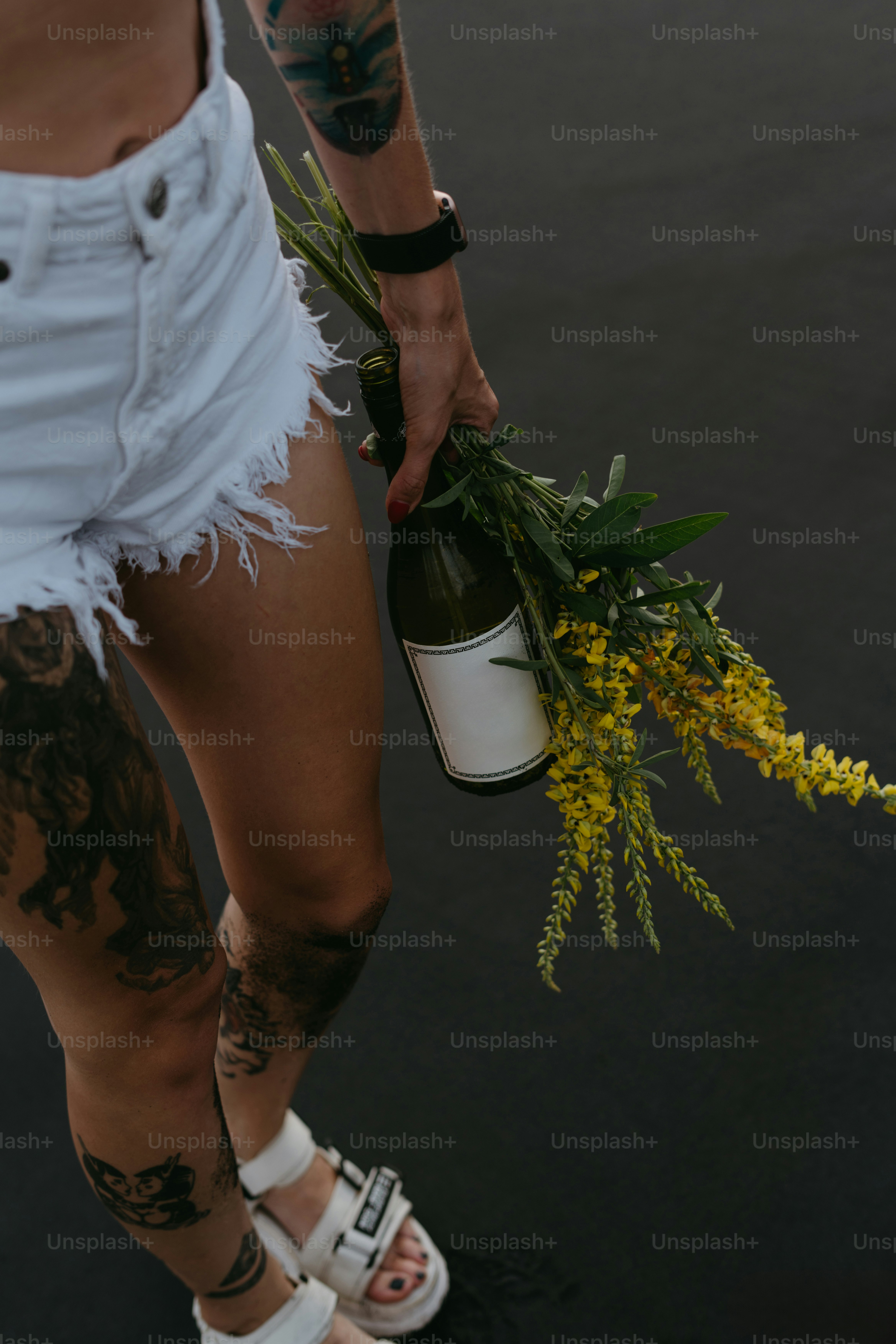 A person with tattoos holding a bottle of wine