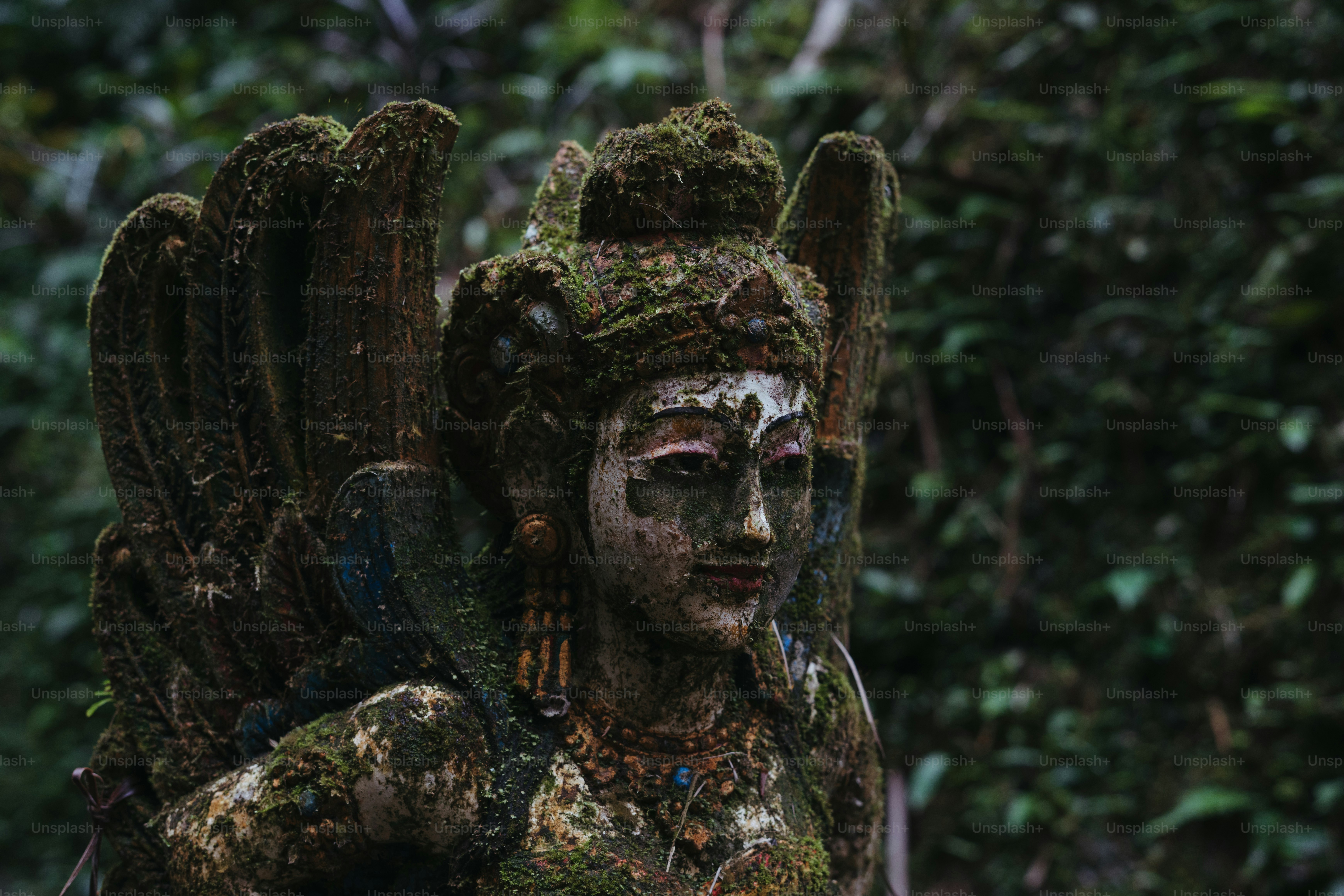 Eine Statue einer Frau, die einen Vogel in einem Wald hält