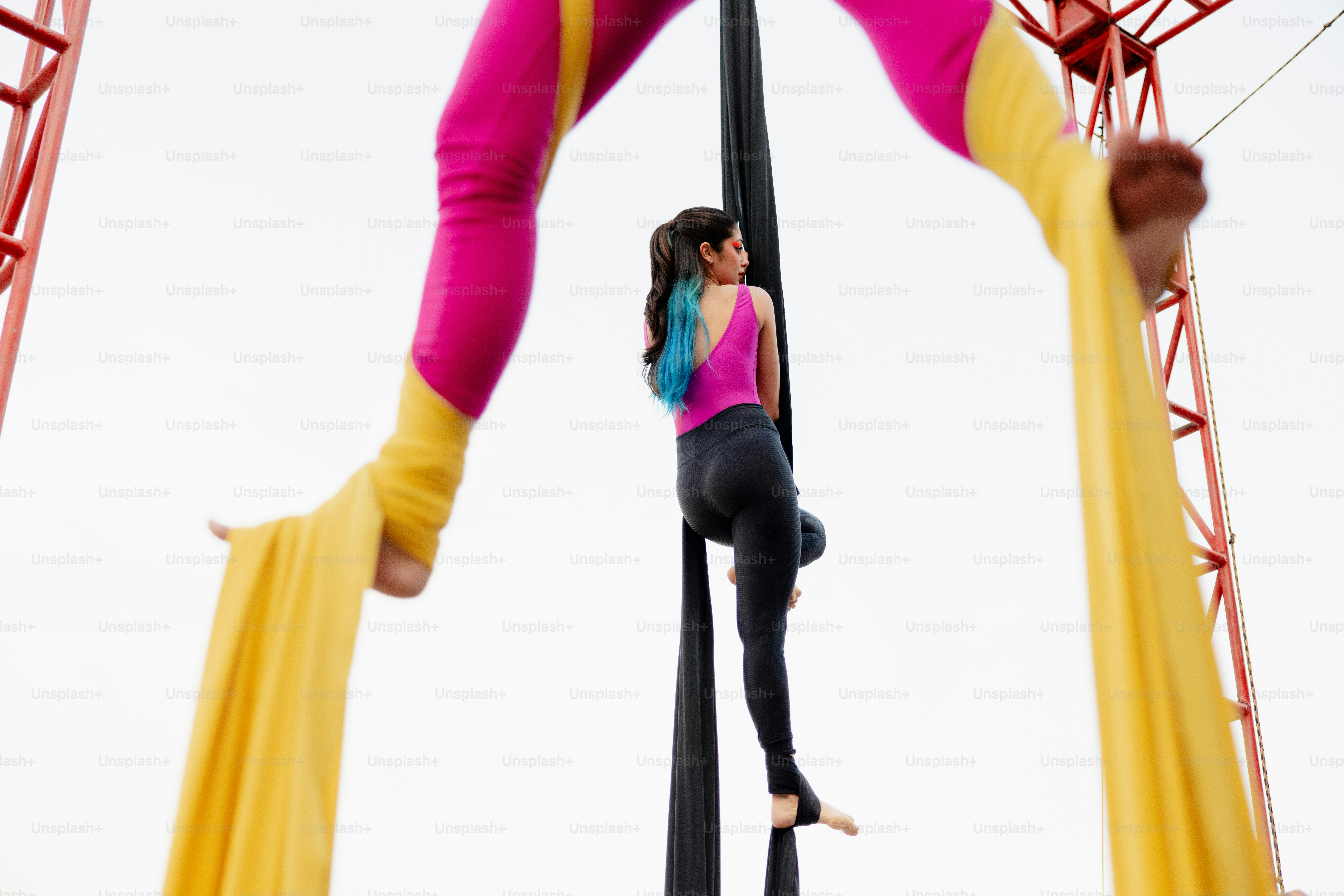 A woman standing on top of a pole next to another woman